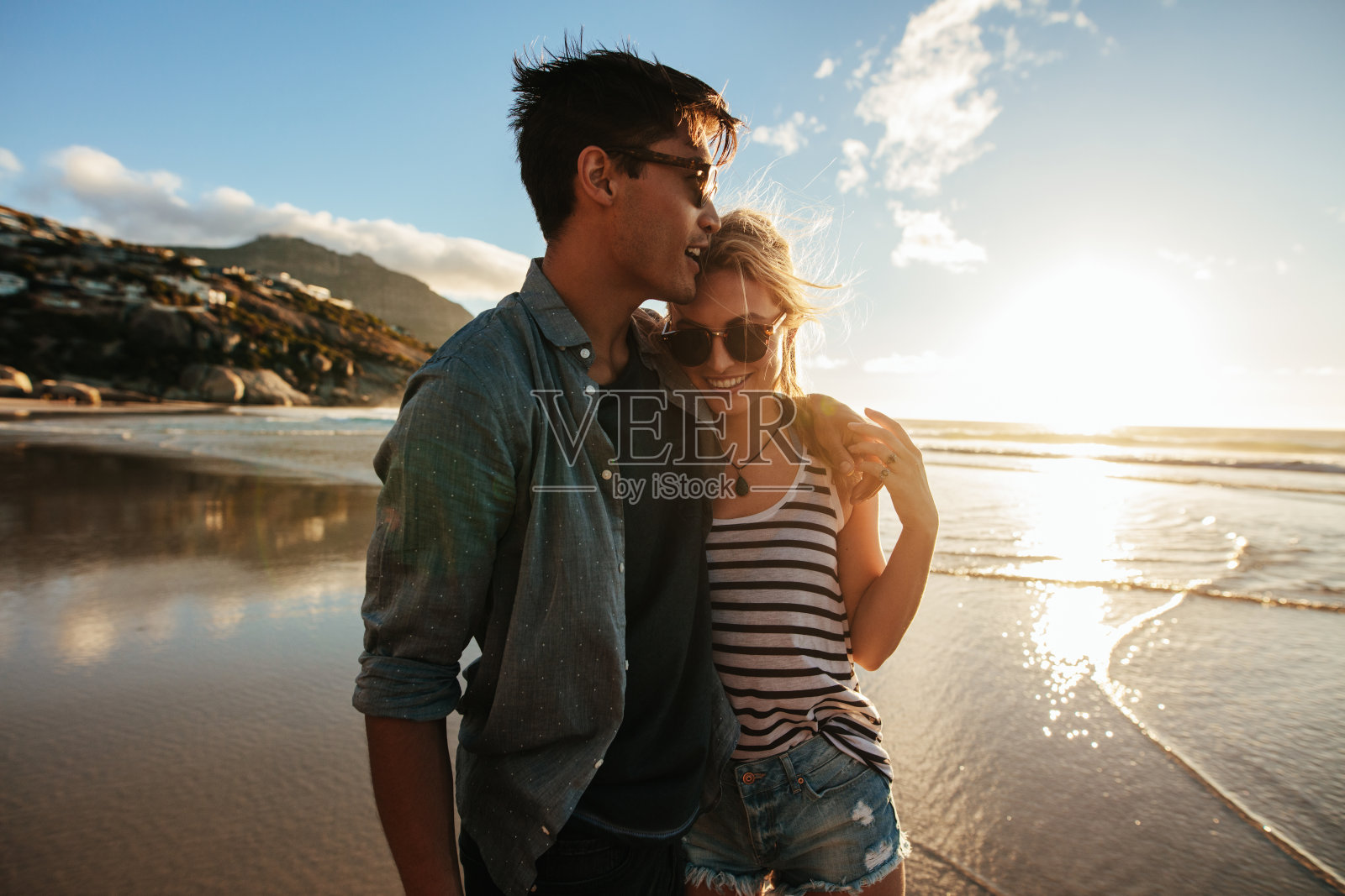 一对浪漫的年轻情侣站在沙滩上照片摄影图片