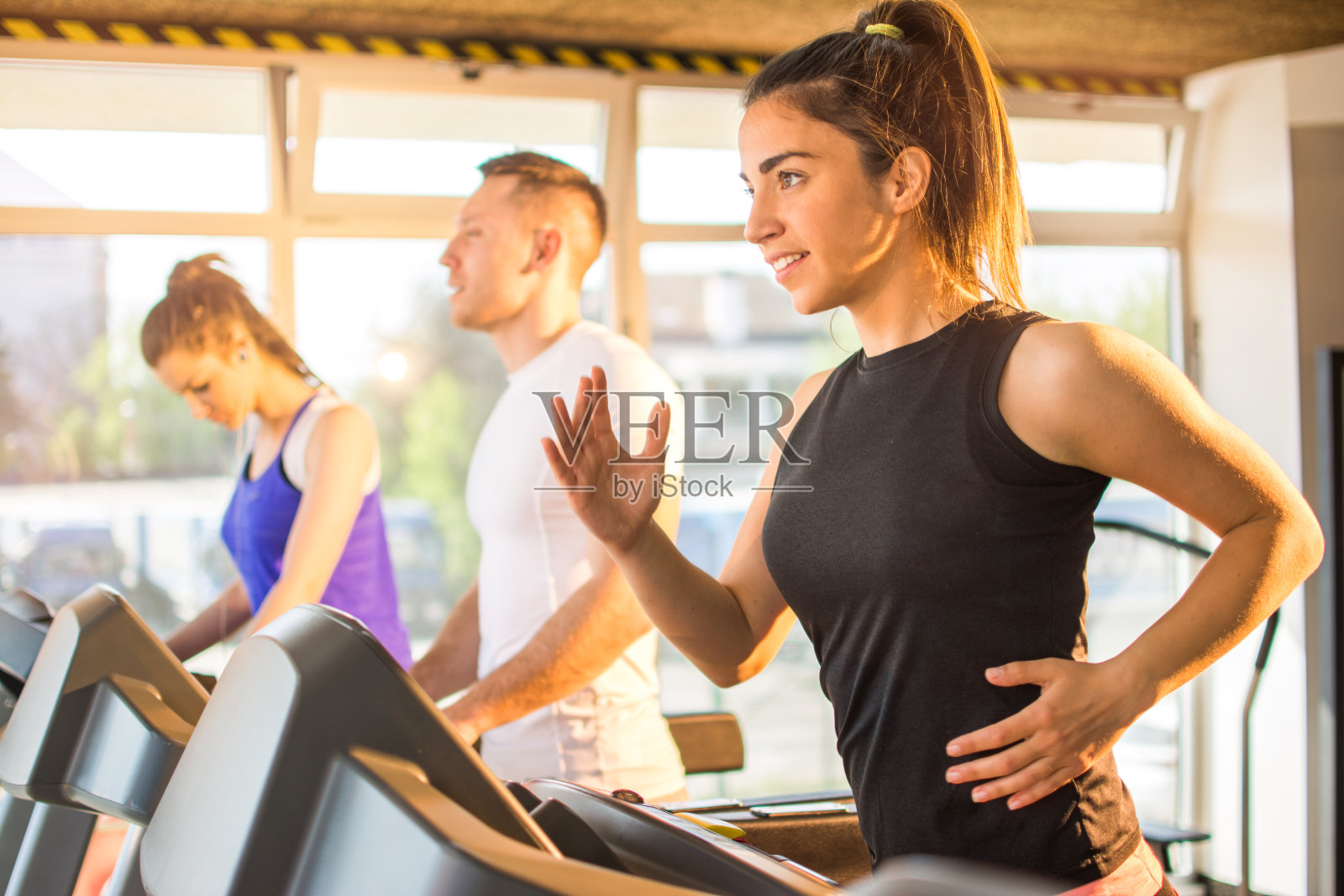 在健身房跑步机上跑步的年轻运动女性。照片摄影图片