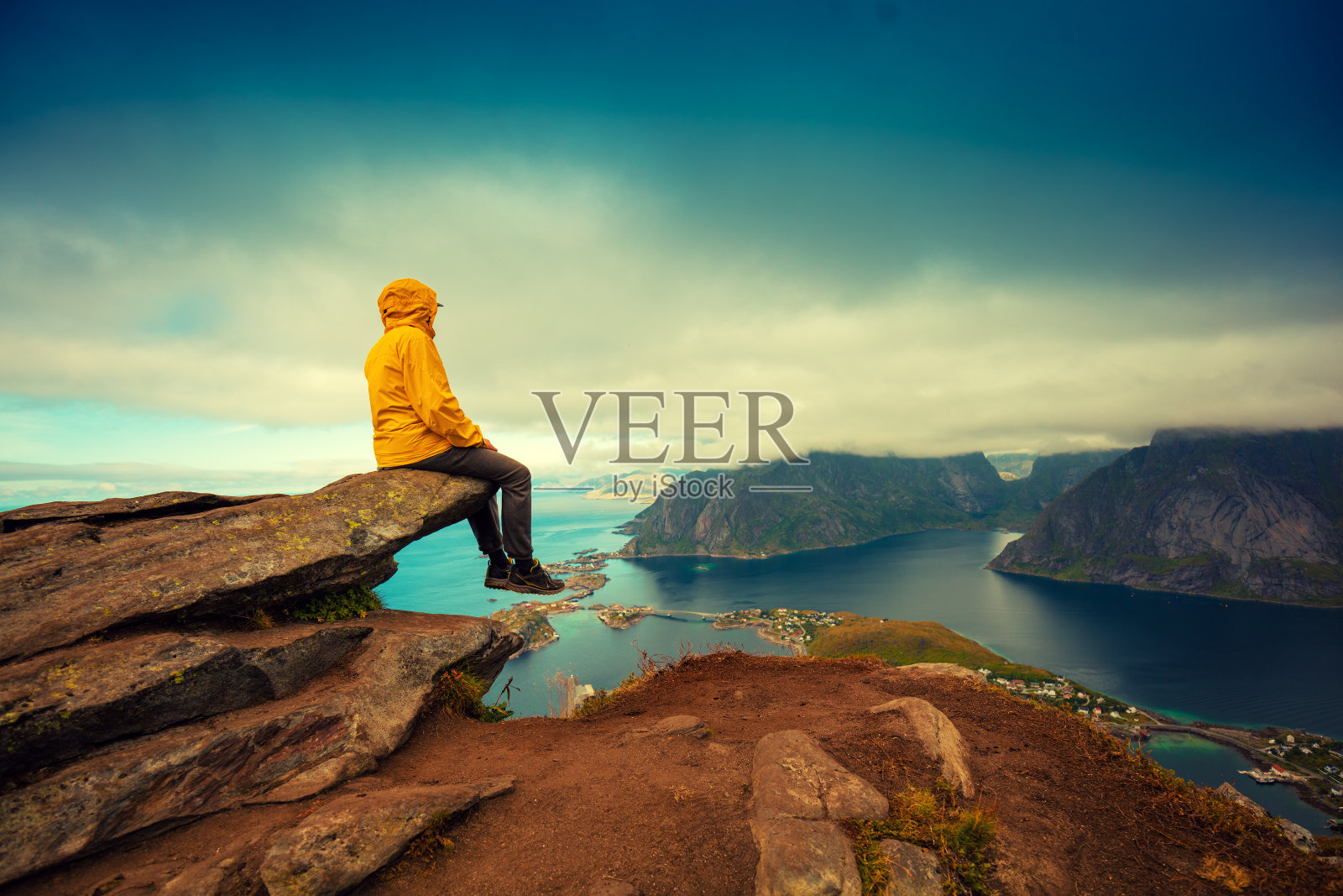 峡湾和渔村全景鸟瞰图。一名游客坐在悬崖峭壁上。美丽的山的风景。挪威自然，罗浮敦群岛。照片摄影图片