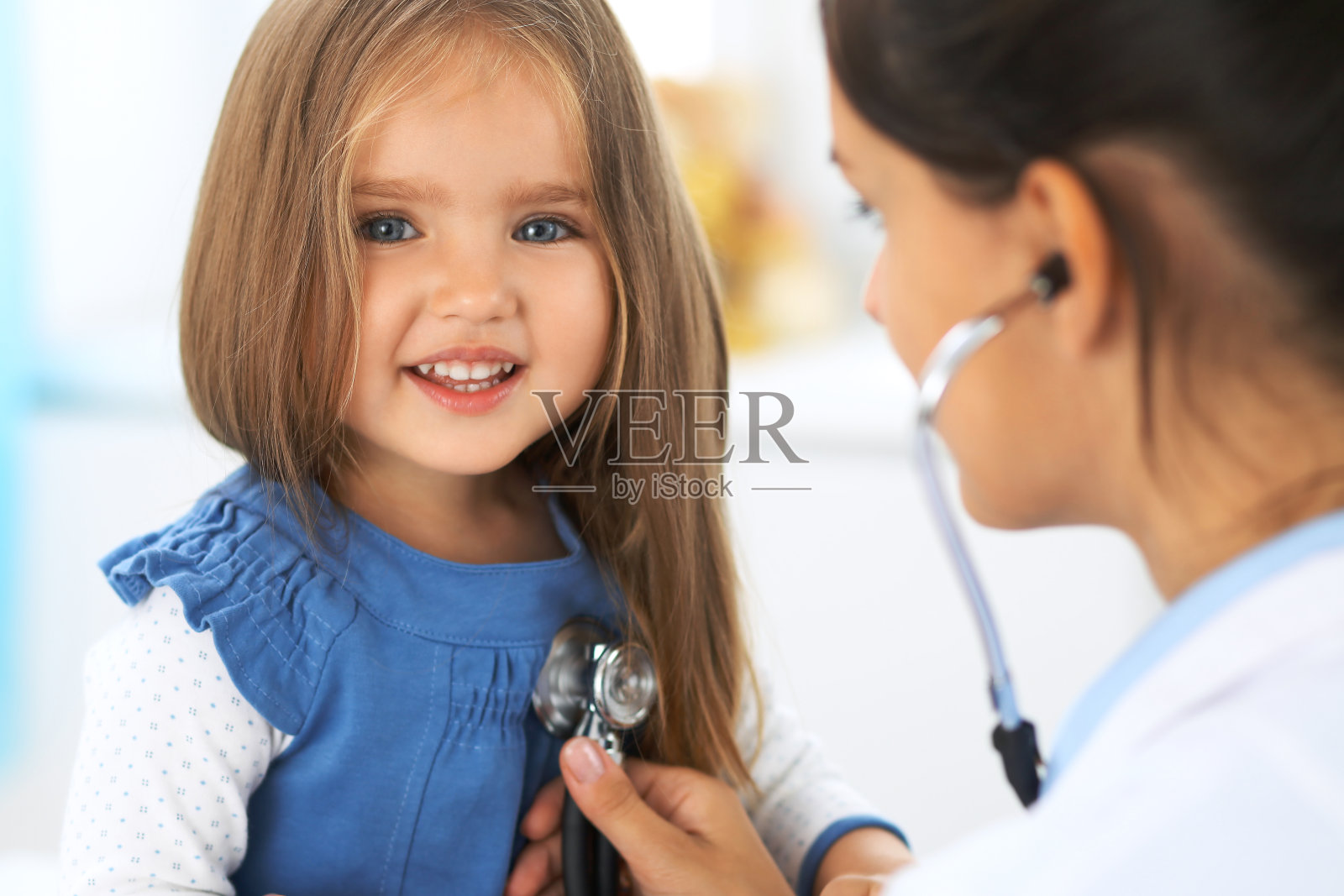 医生正在用听诊器检查一个小女孩照片摄影图片