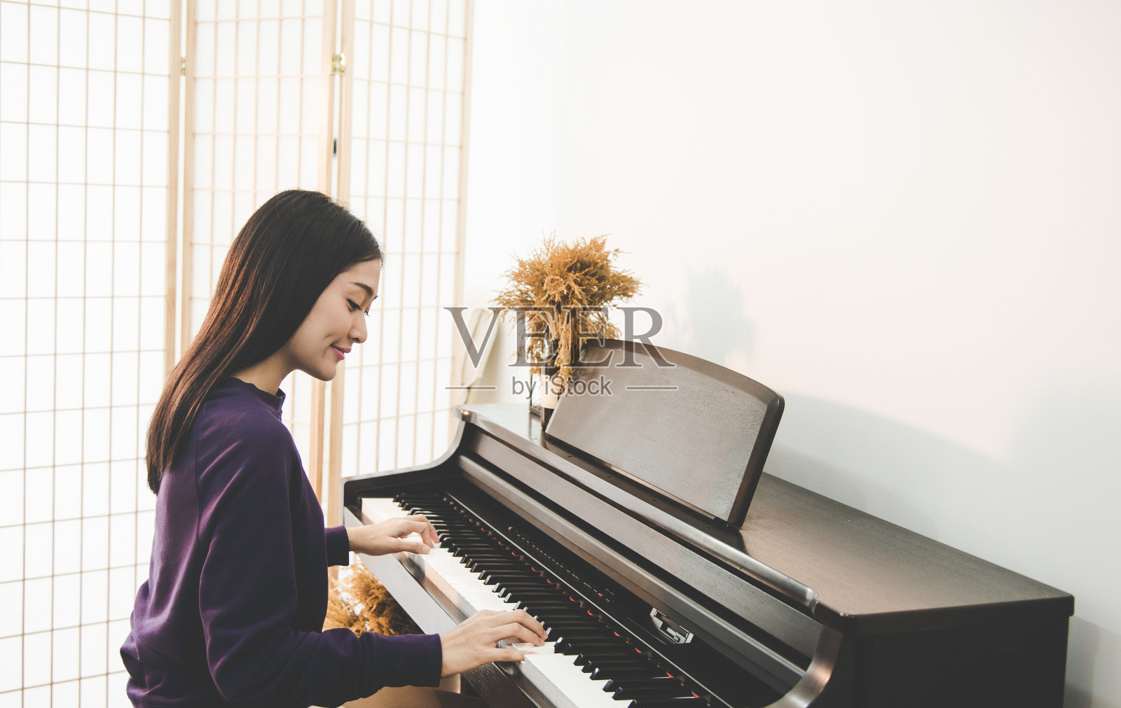 年轻漂亮的亚洲女孩坐在钢琴前照片摄影图片