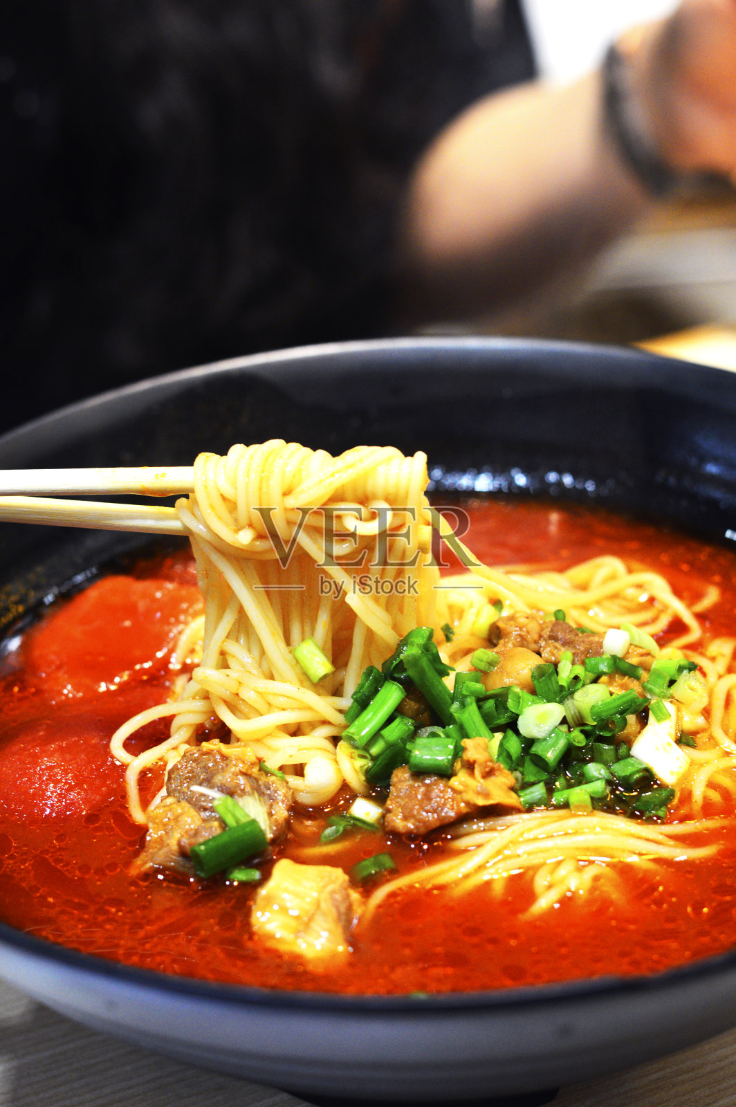 筷子从大碗里夹起中国番茄牛肉面照片摄影图片