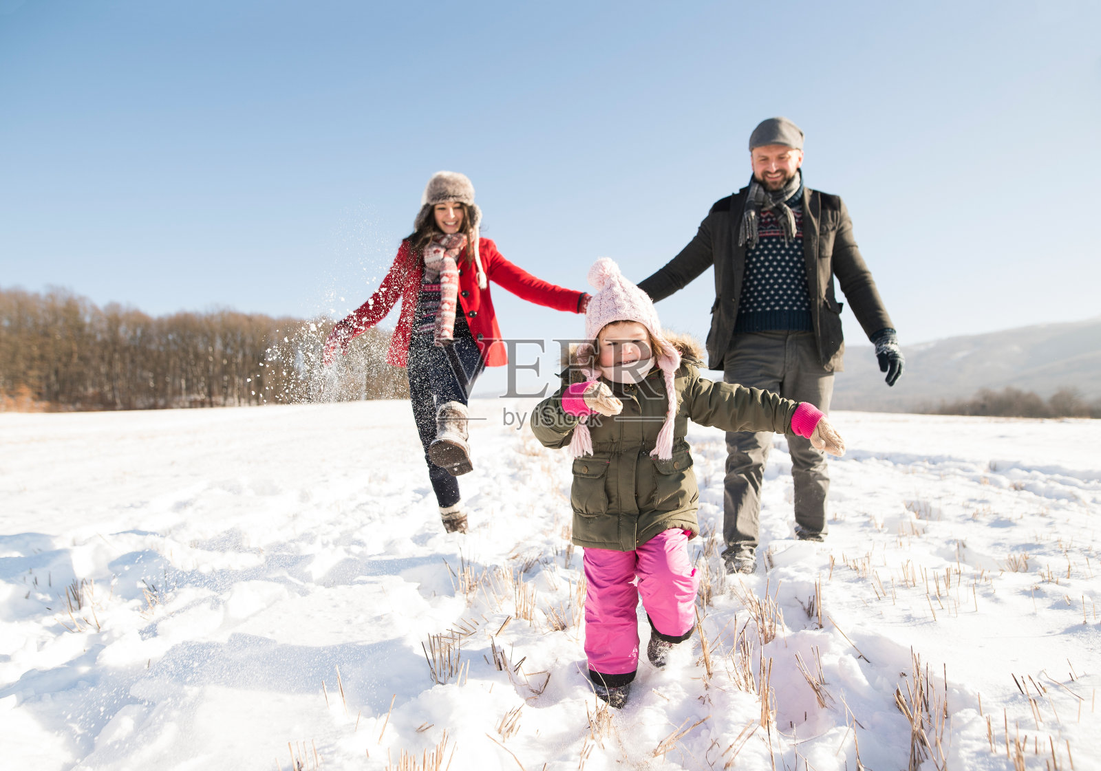 爸爸和妈妈和他们的女儿，在雪中玩耍。照片摄影图片