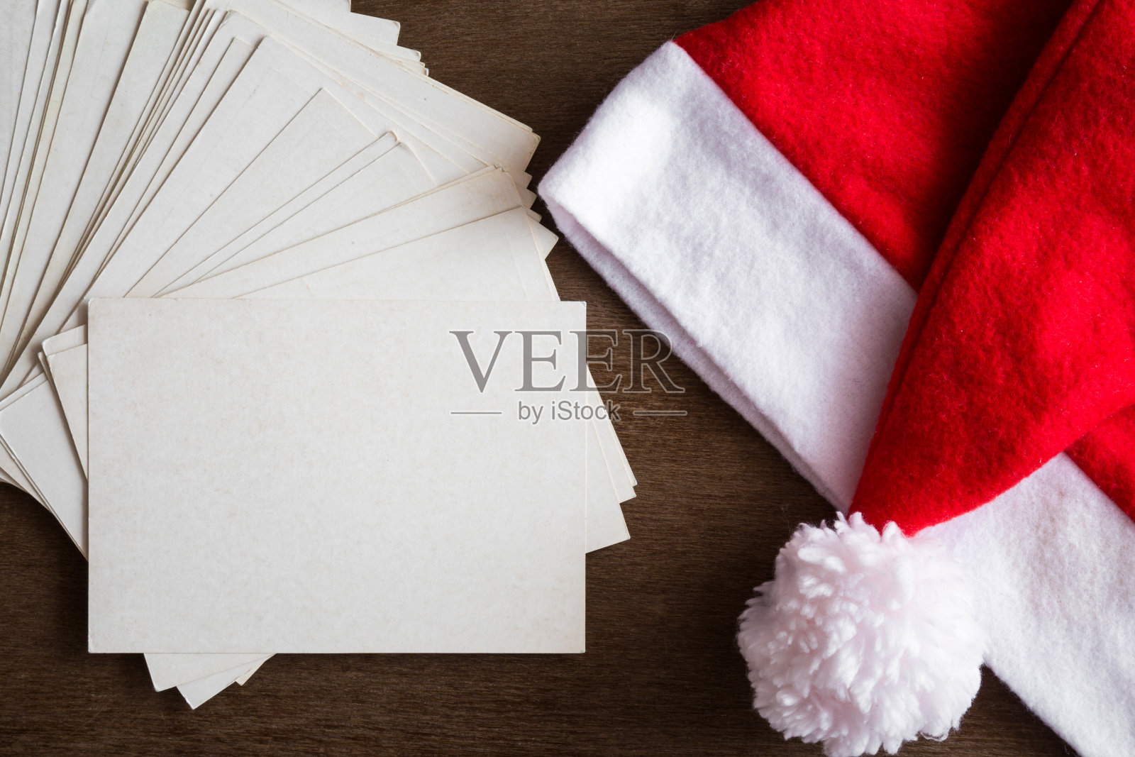 白色空白贺卡和红帽子。孩子和大人写给圣诞老人的信。圣诞晚会的邀请。圣诞节的时间概念。文本的空位置。前视图。照片摄影图片