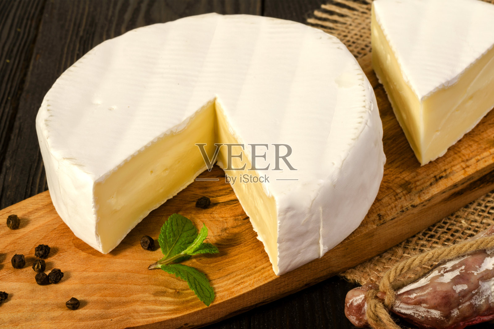 圆的卡芒贝尔奶酪，切片，放在木板上，fuet香肠，放在木板上，带袋子。照片摄影图片