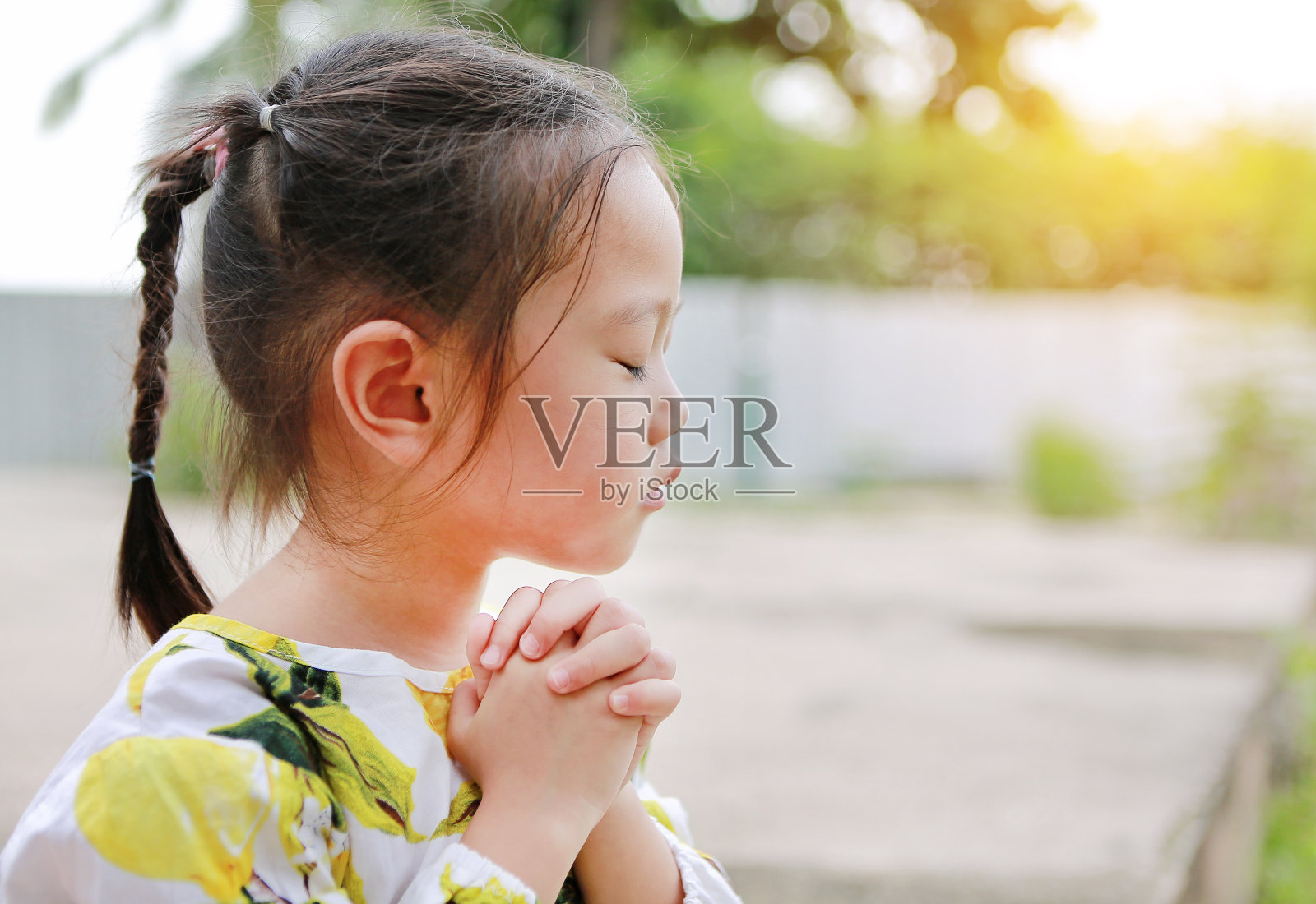 可爱的亚洲小女孩在花园里祈祷。灵性和宗教。照片摄影图片