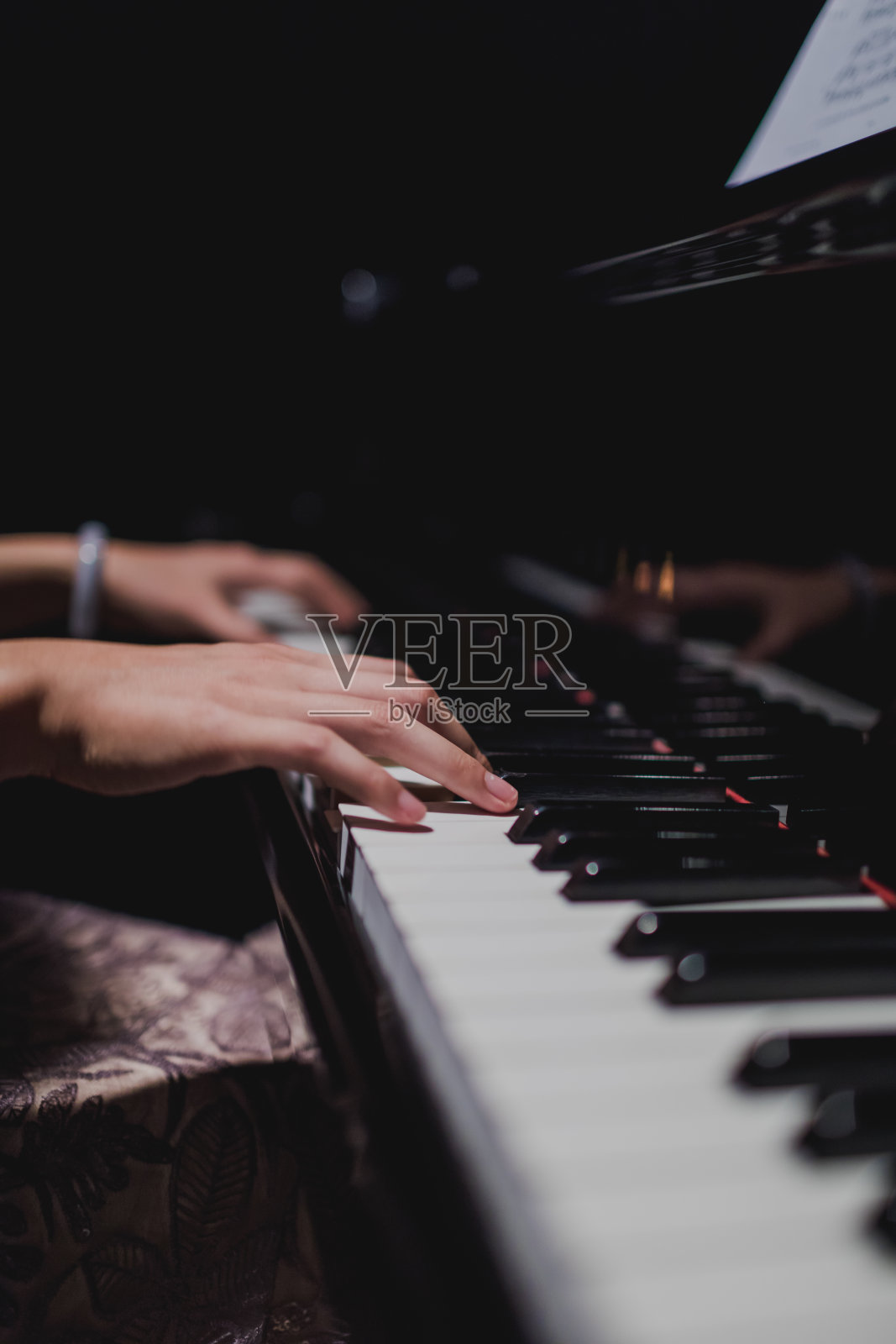 女钢琴家的手在钢琴键盘上。照片摄影图片