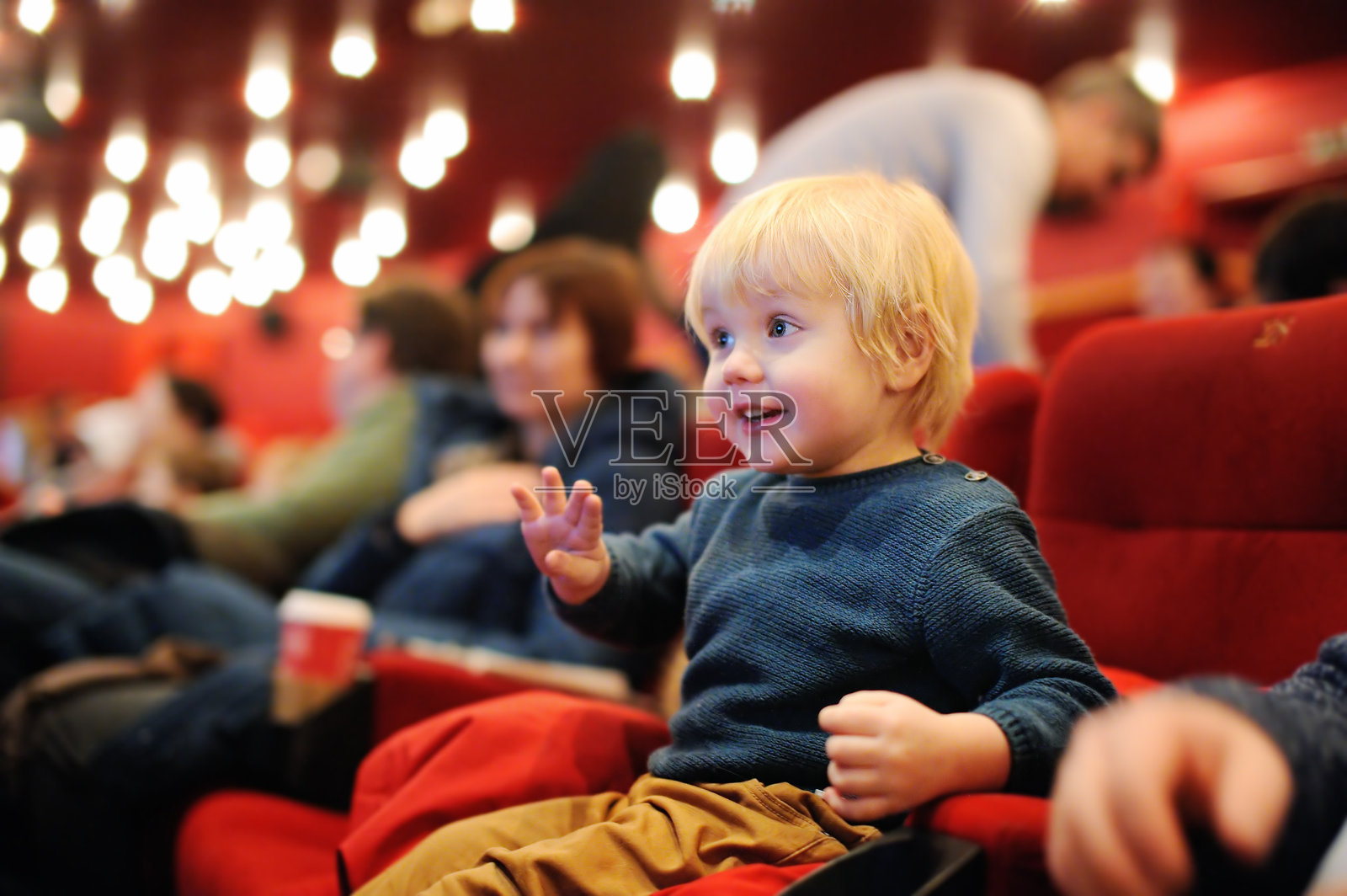 可爱的蹒跚学步的小男孩在电影院看卡通电影照片摄影图片