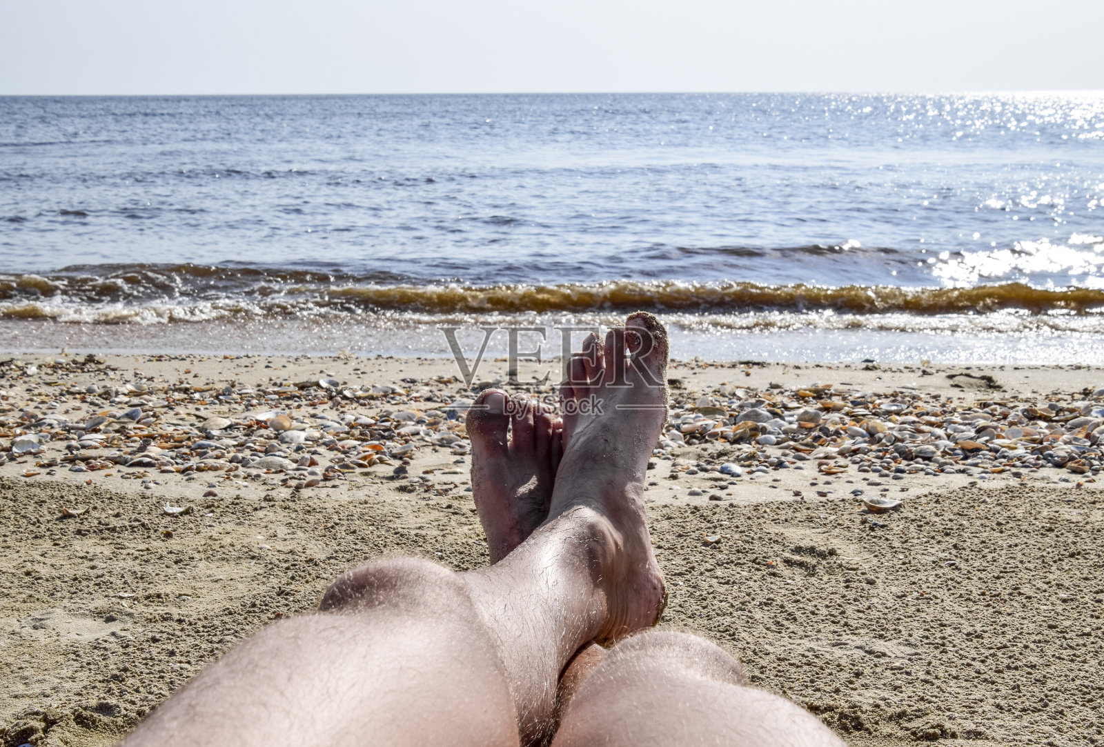 沙滩上一个男人的腿。一个男人躺在沙滩上休息。腿在框架里。照片摄影图片