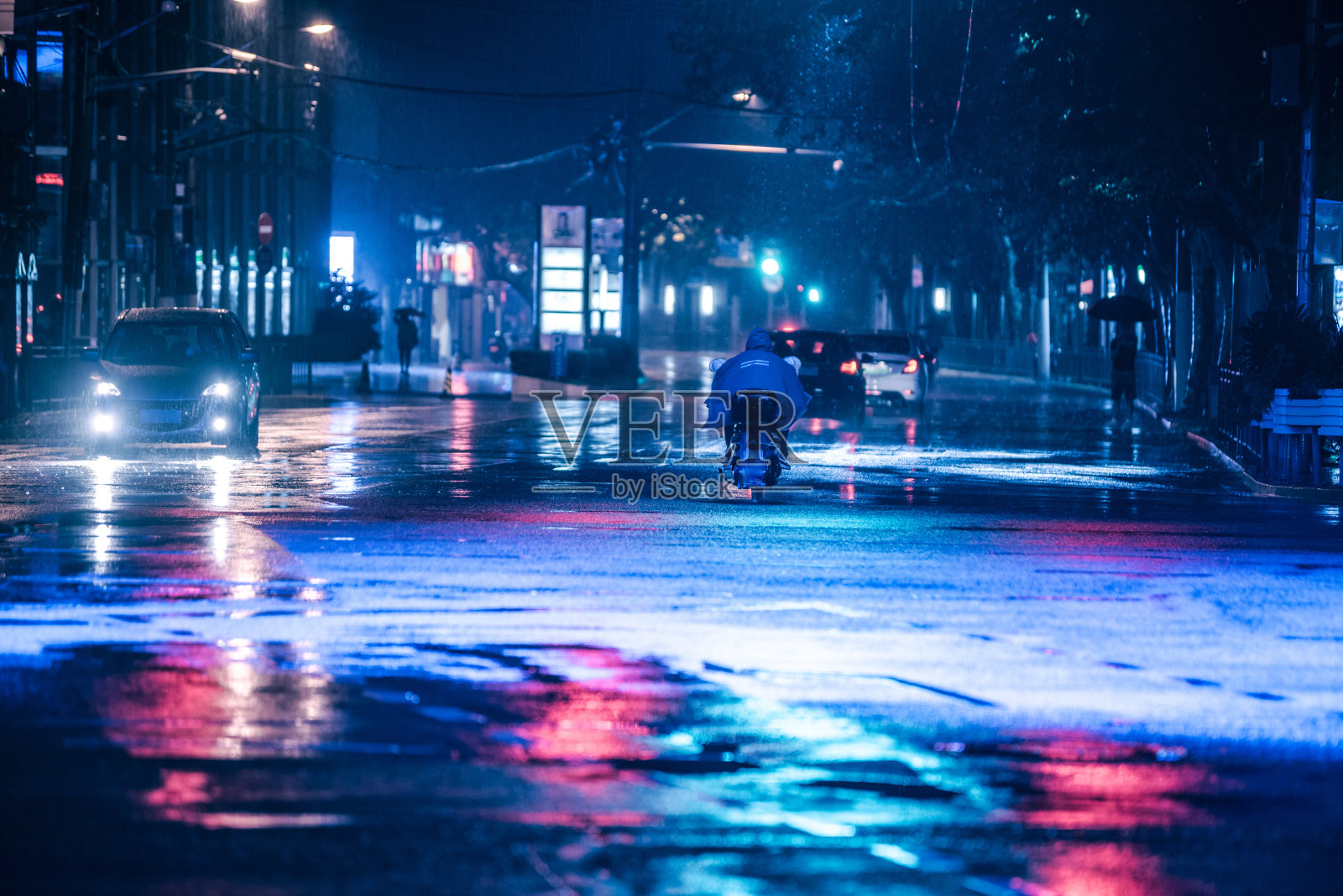 汽车在雨中行驶在潮湿的路面上，彩色的灯光反射在潮湿的柏油路上照片摄影图片