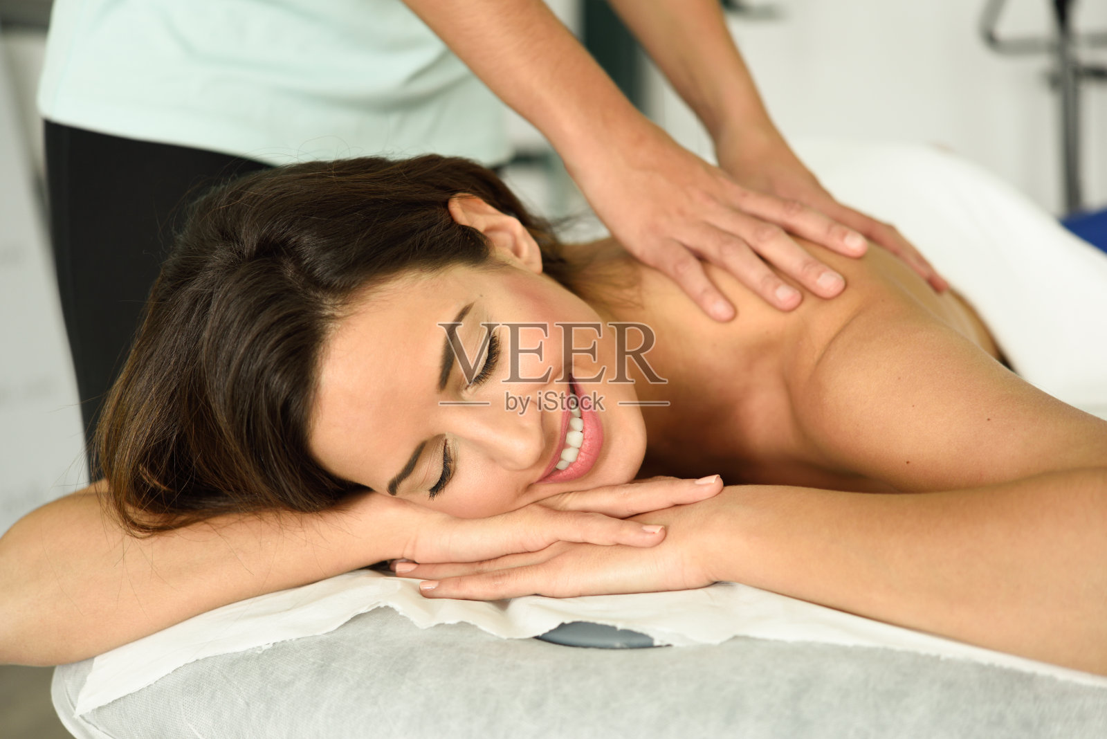 年轻女性接受放松背部按摩在水疗中心。照片摄影图片