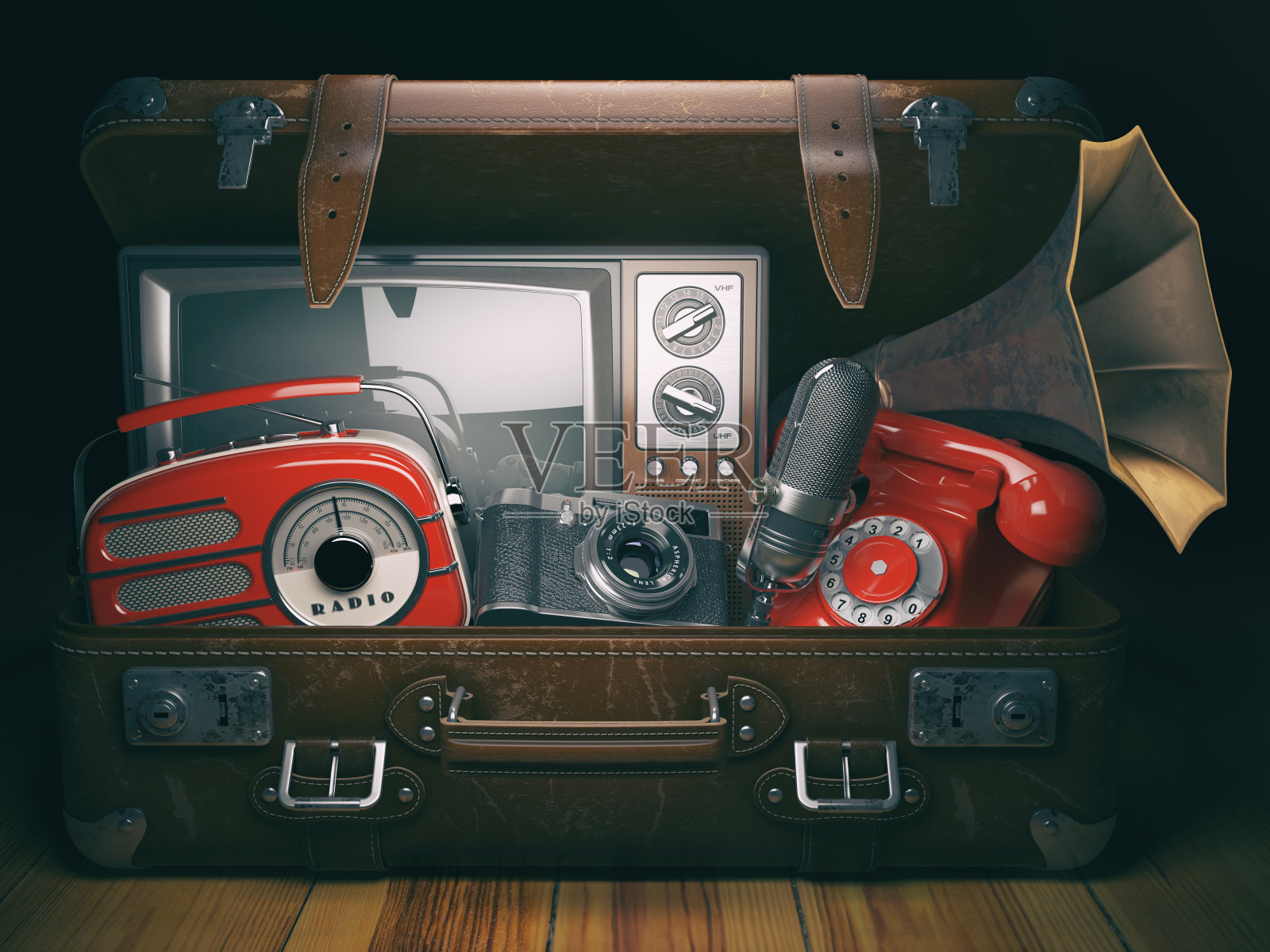 老式行李箱，带有陈旧过时的电子设备。复古技术概念背景。收音机、电视机、电话、摄像机、麦克风和留声机。照片摄影图片