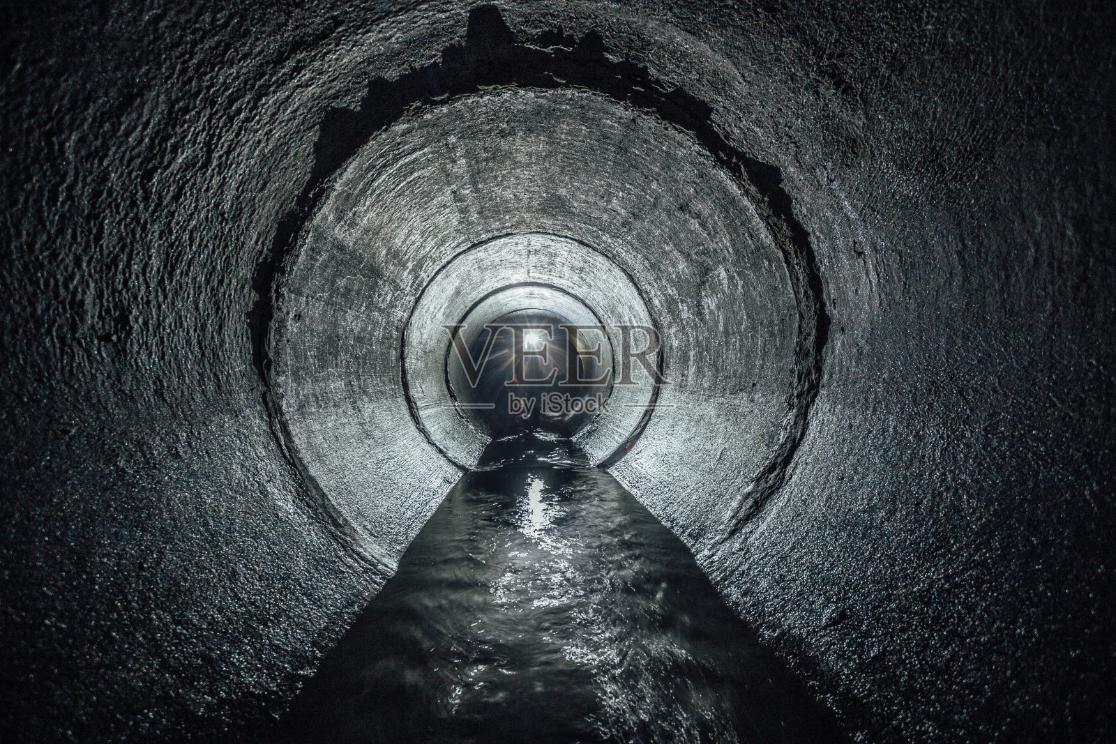 地下河流在圆形混凝土下水道隧道中流动。污水收集照片摄影图片