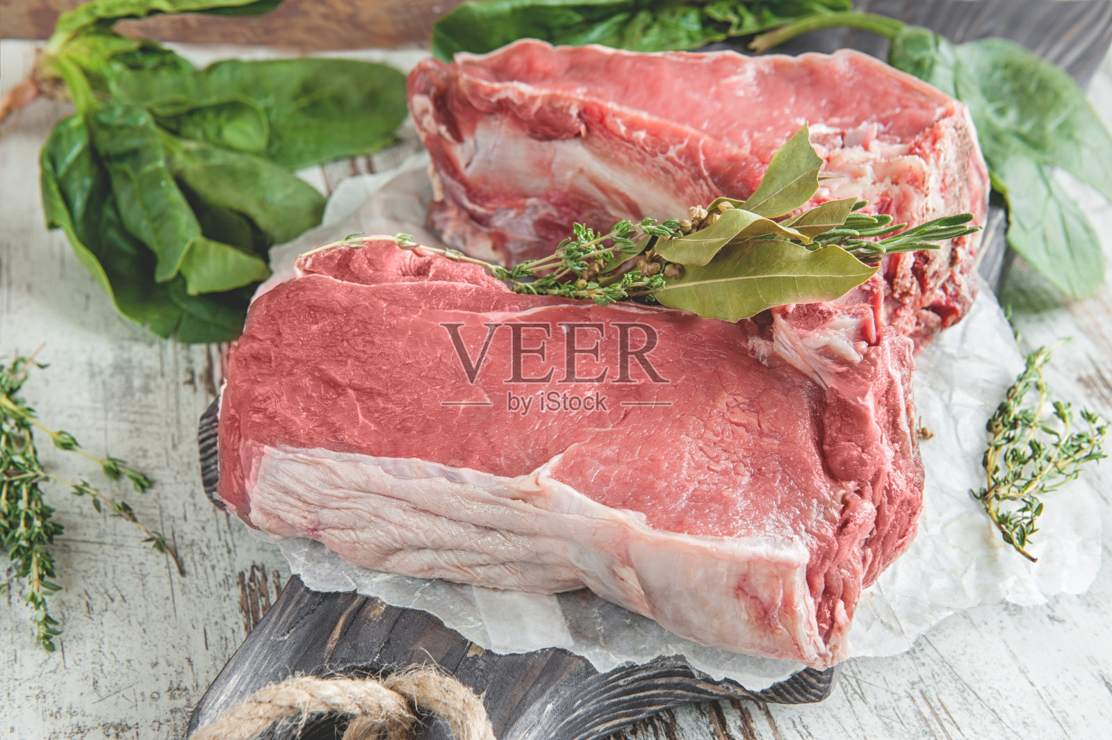 将切好的牛肉放在木砧板上烤，用菠菜、迷迭香和普罗旺斯香草做腌料照片摄影图片