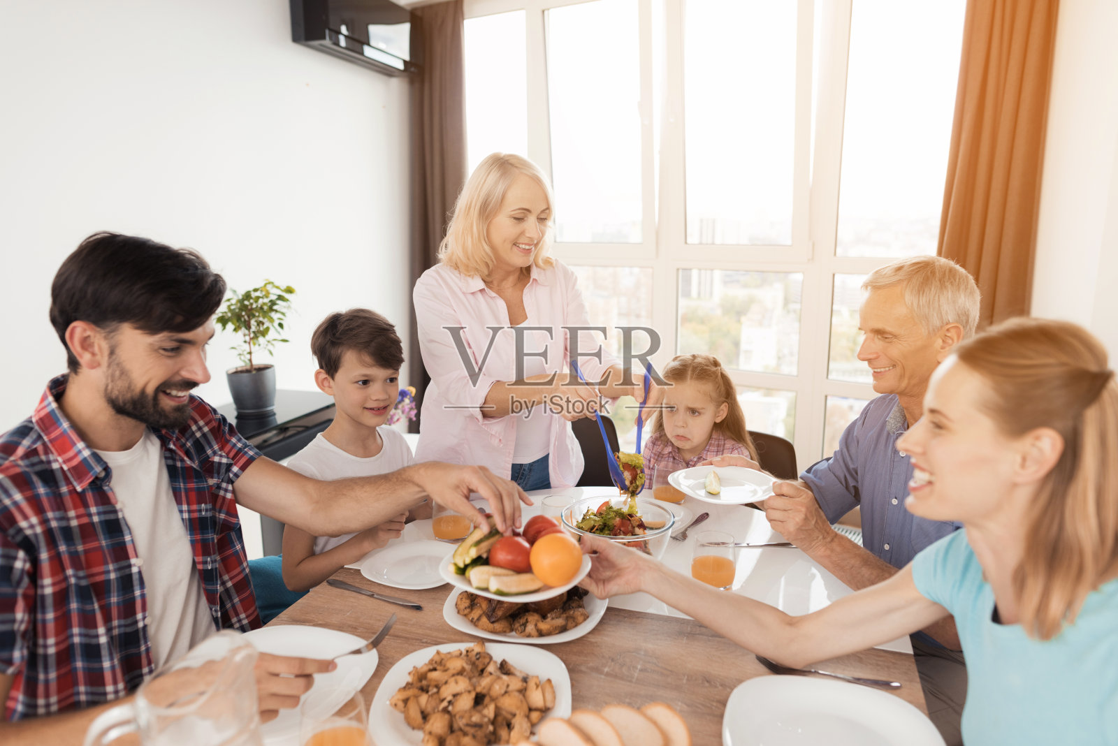 全家人聚在一起吃感恩节的节日晚餐。每个人都把食物放在盘子里照片摄影图片