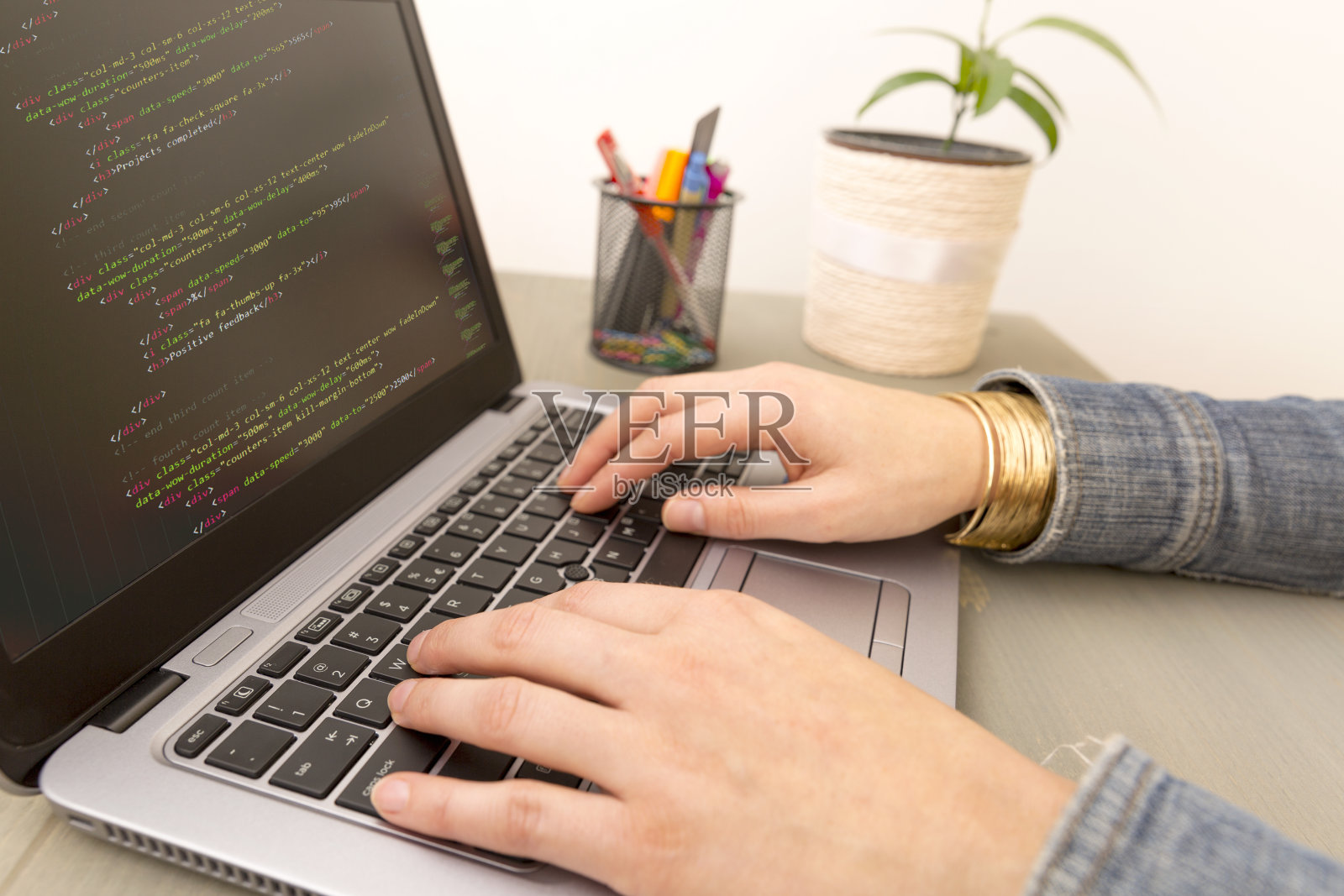编程工作时间。程序员输入新的HTML代码行。笔记本电脑和手特写。工作时间。网站设计的商业概念。照片摄影图片
