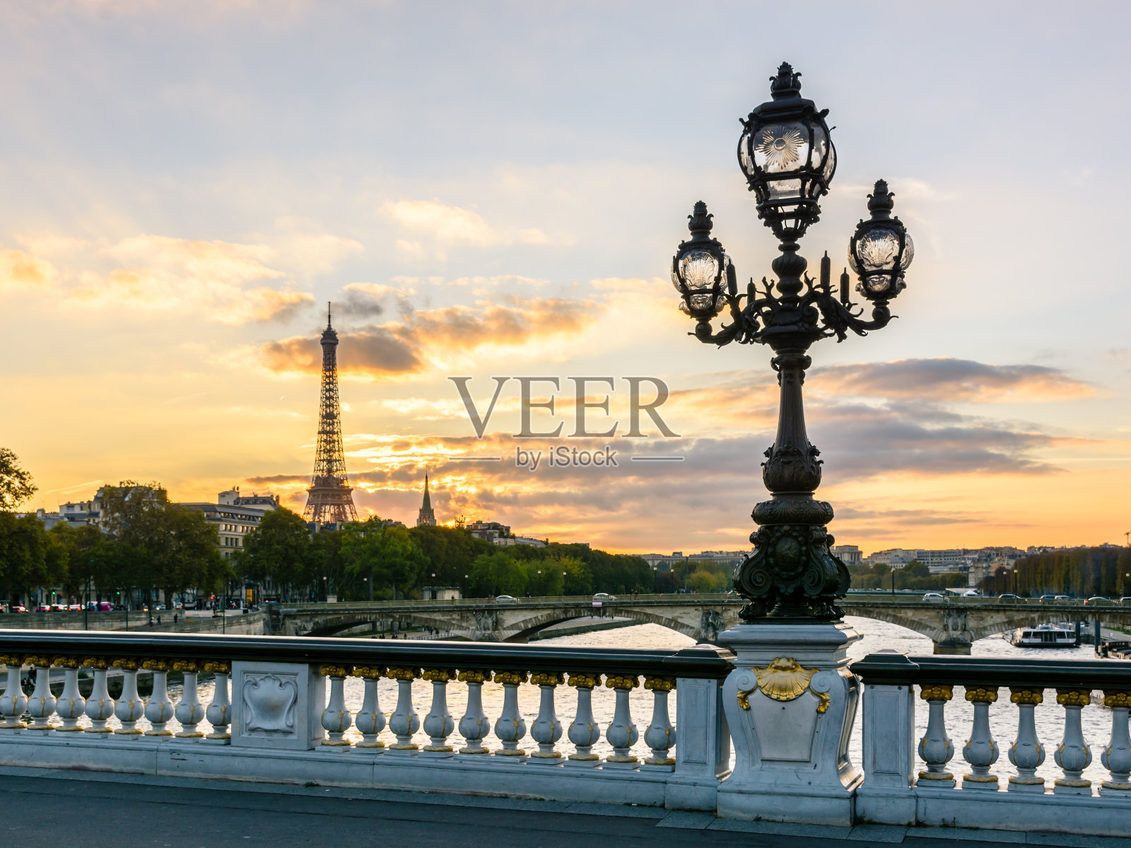 这是巴黎亚历山大三世桥上的一盏新艺术风格的路灯，夕阳西下时以埃菲尔铁塔为背景照片摄影图片