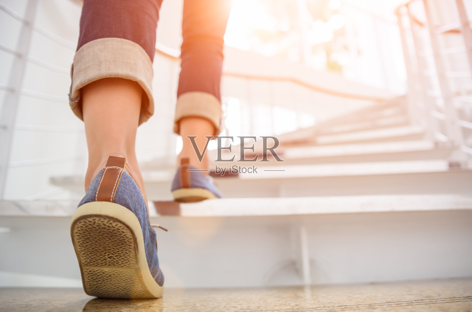 年轻的成年女子走上楼梯与太阳运动的背景。照片摄影图片