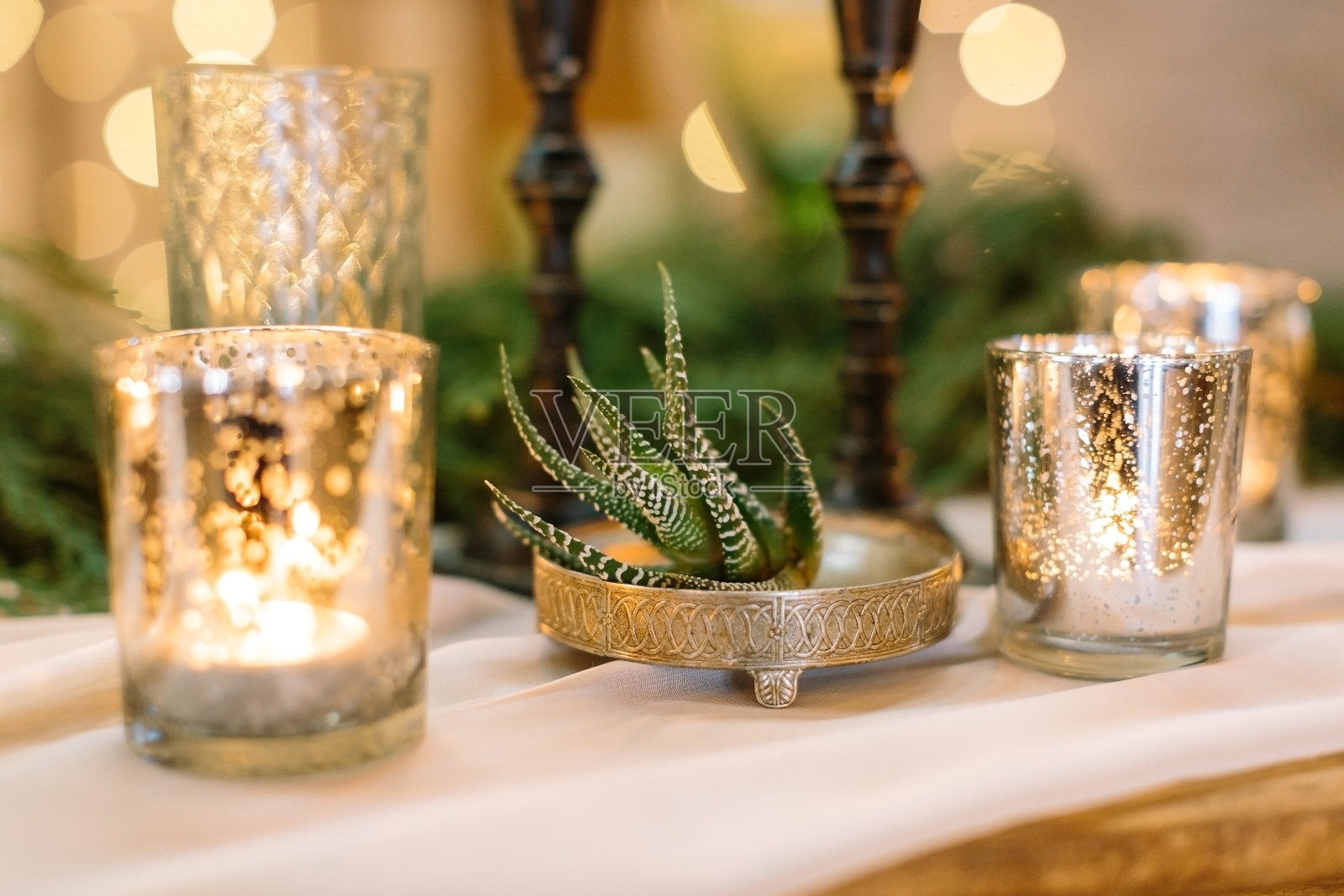 植物、装饰、灯光概念。在奇妙的银盘子上有原始装饰有小绿色多肉，它被透明的烛台包围着，火焰进入他们照片摄影图片