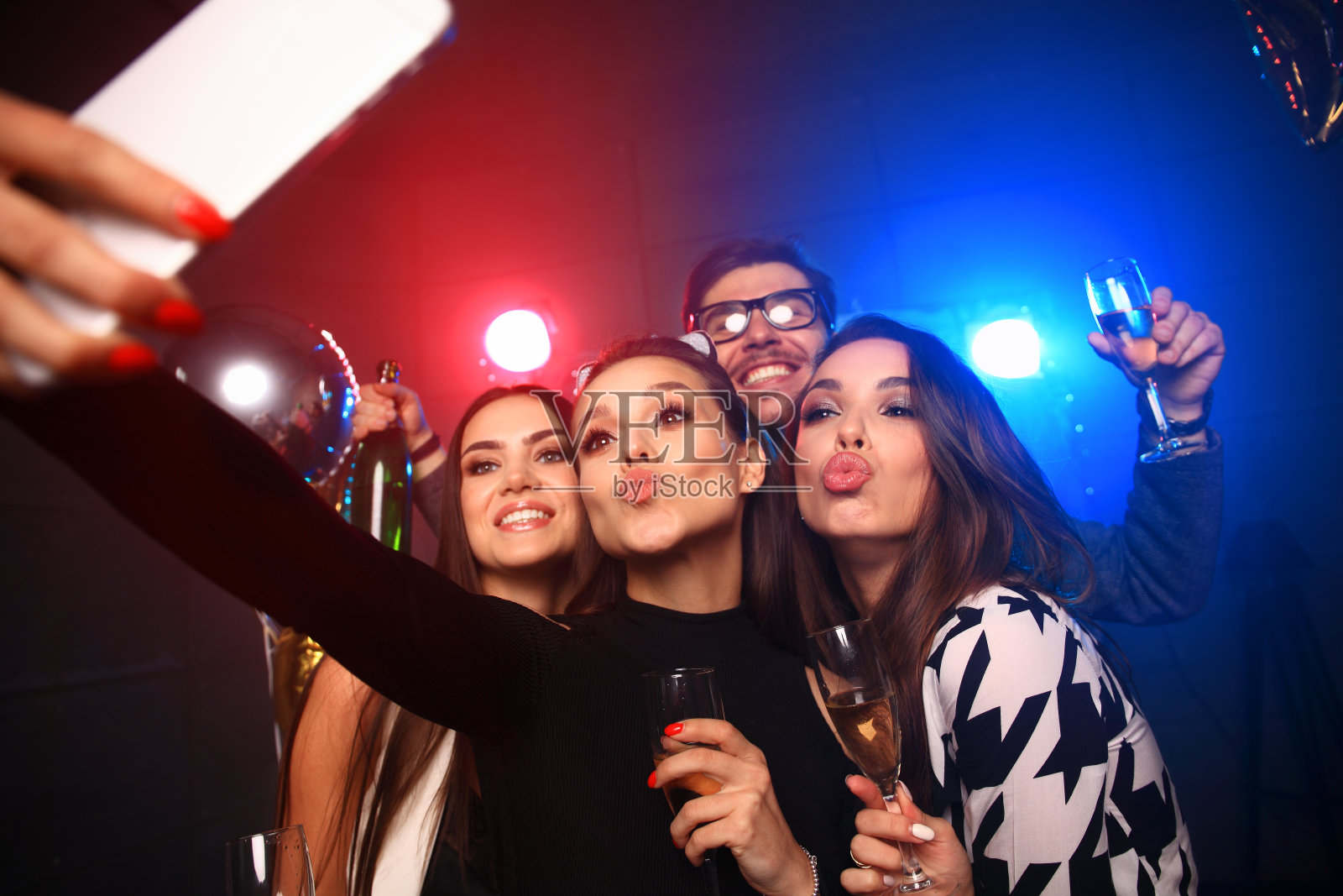 派对，科技，夜生活和人的概念-微笑的朋友与智能手机在俱乐部自拍。照片摄影图片