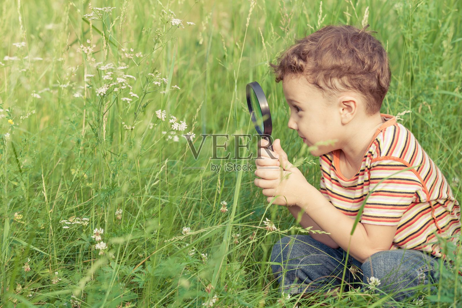 快乐的小男孩用放大镜探索大自然照片摄影图片