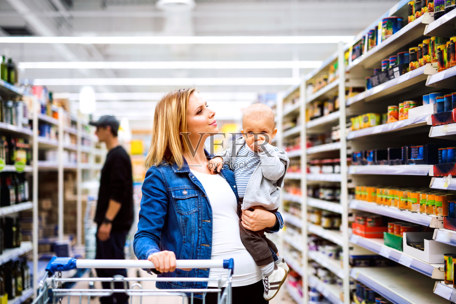 年轻的母亲和她的小男孩在超市。照片摄影图片
