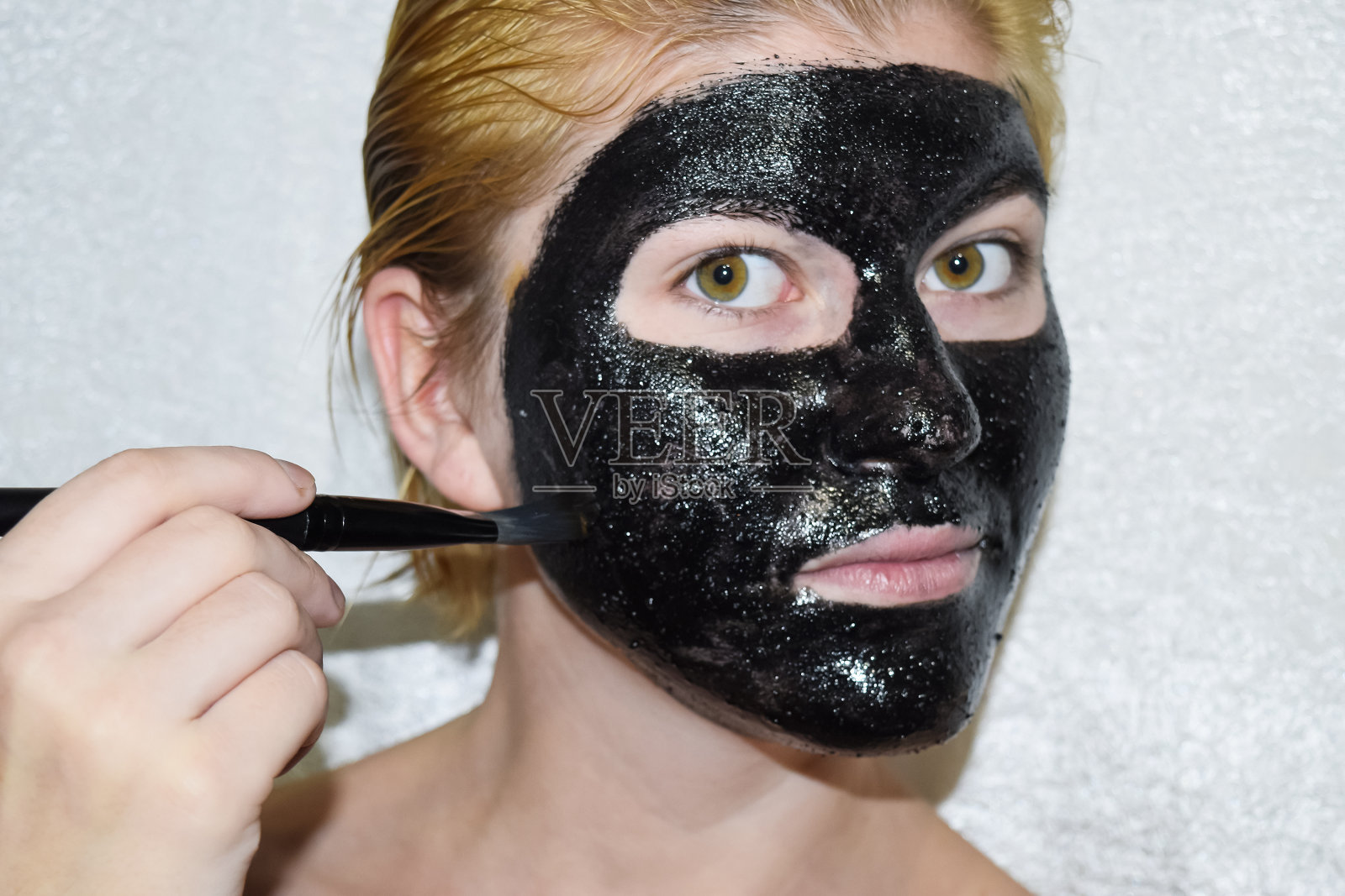 戴着黑色化妆面具的女孩。阿司匹林和活性炭洁面面膜。黑色化妆面膜。照片摄影图片
