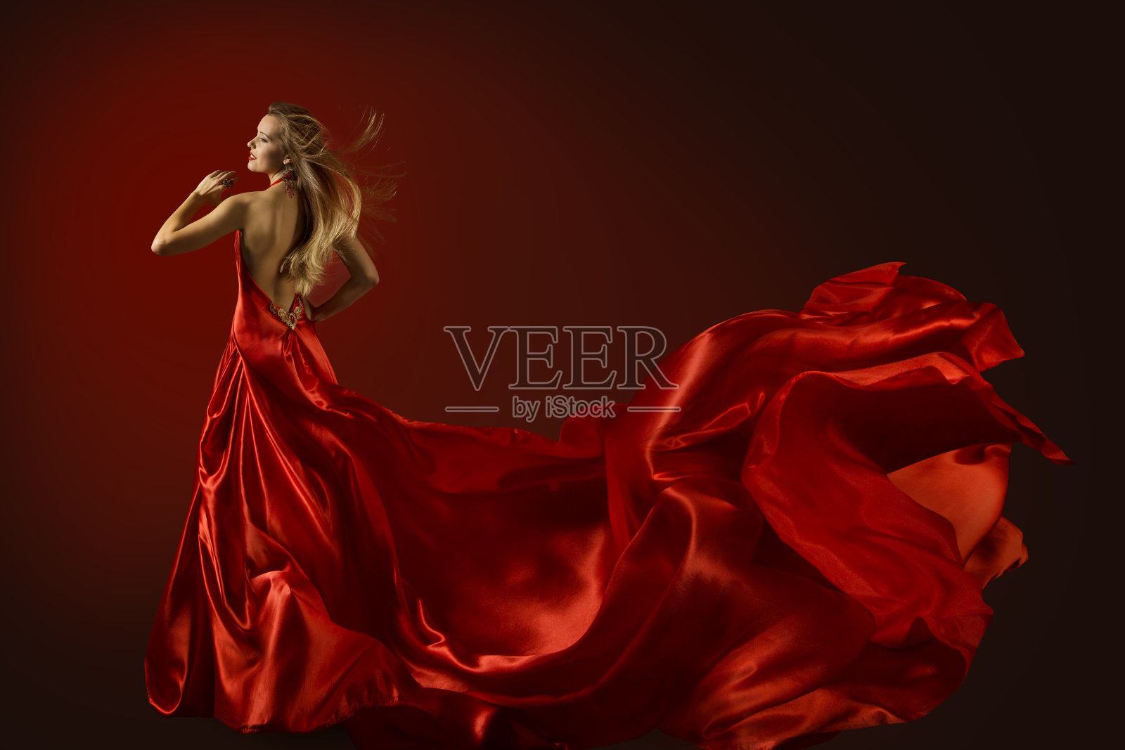 时装模特跳舞在红色的裙子，快乐跳舞的女人飞飘动的织物，后视图照片摄影图片
