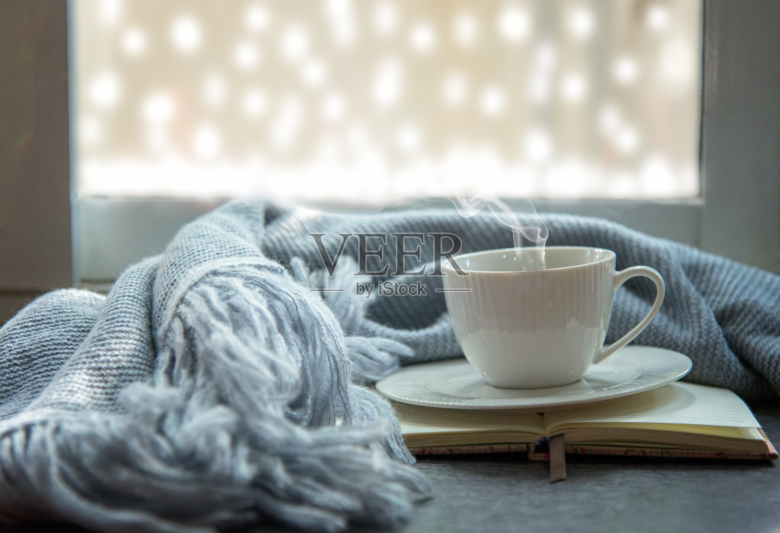 舒适的冬天。白色的一杯热咖啡和打开的书与温暖的格子在古董窗台。生活方式的概念。照片摄影图片