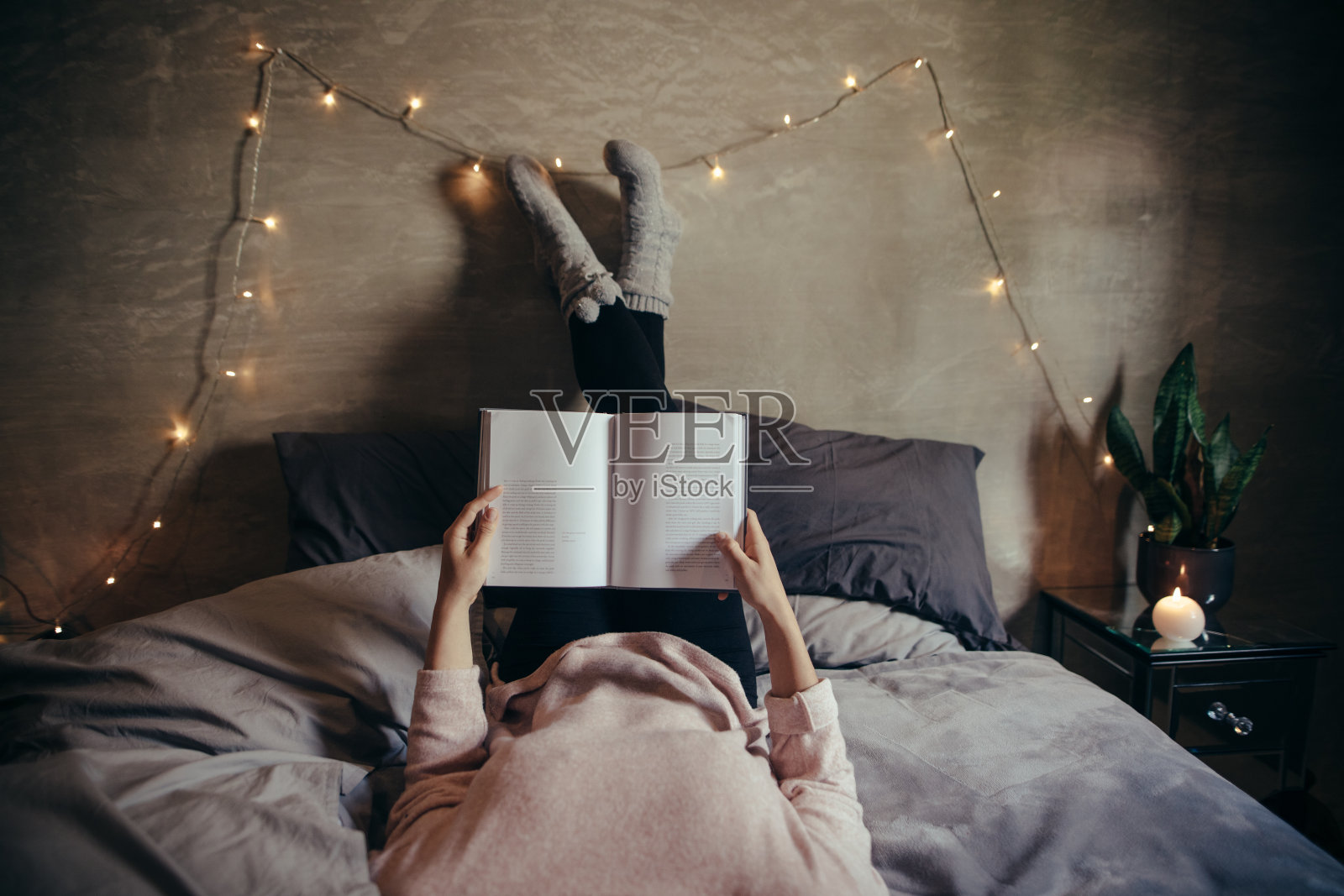 女人躺在床上看书。照片摄影图片