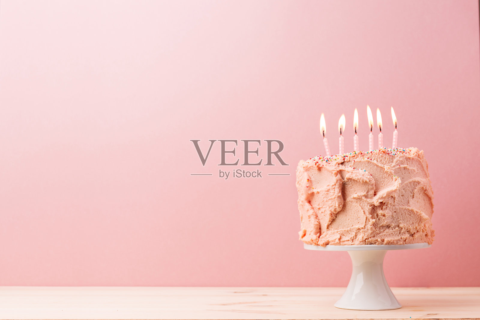 粉红色生日蛋糕和燃烧的蜡烛照片摄影图片