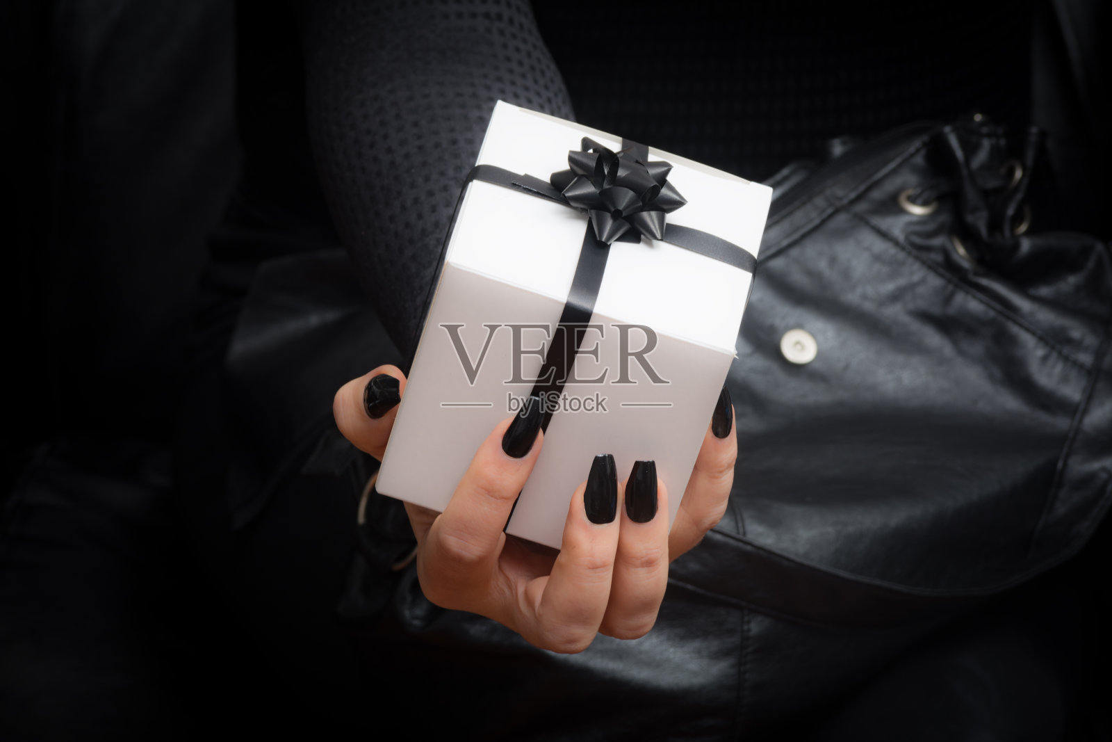 黑衣女子拿着白丝带和黑丝带玫瑰的白礼物照片摄影图片