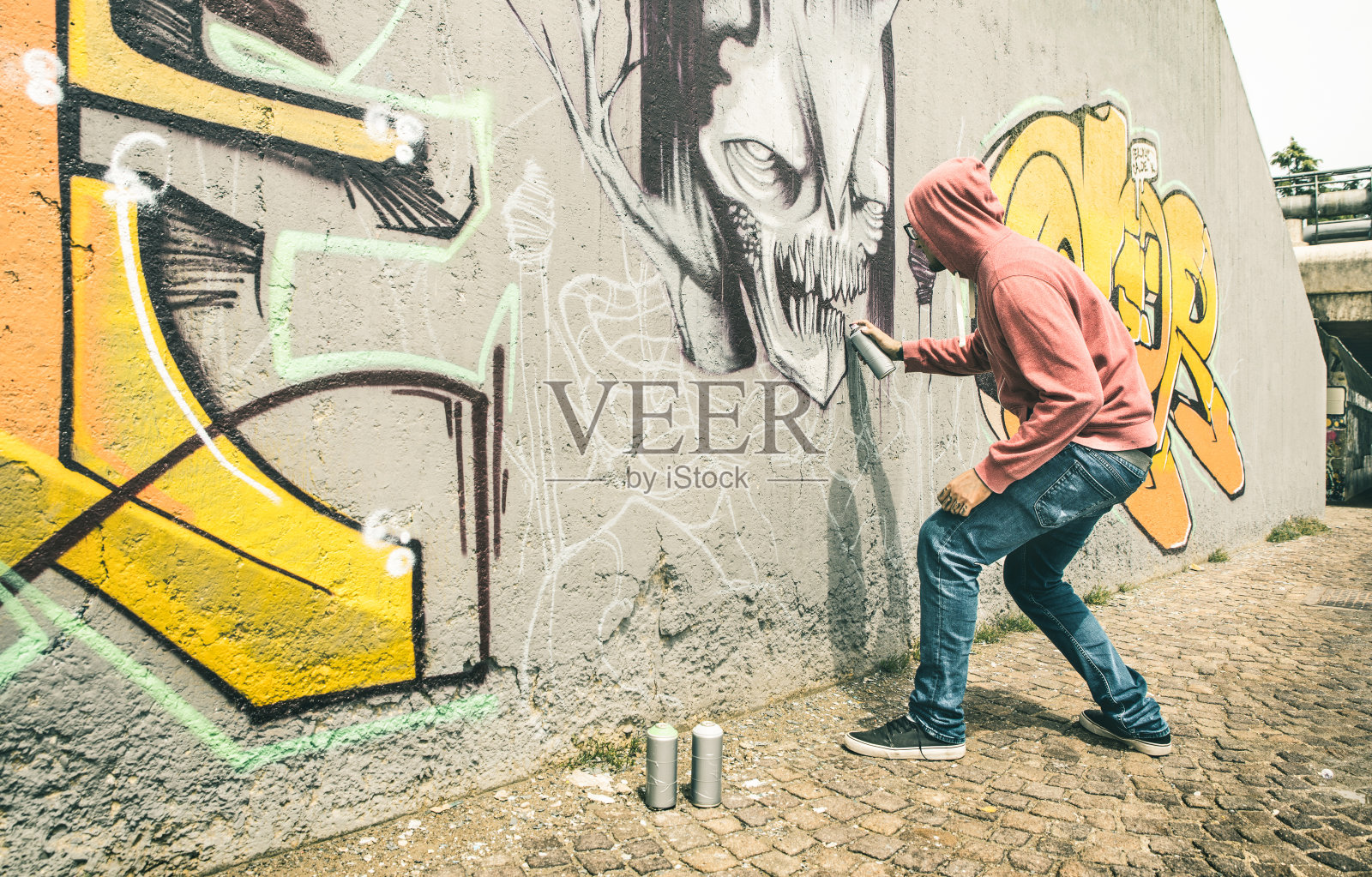 街头艺术家在普通的墙上画彩色涂鸦-现代艺术概念与城市人表演和准备活壁画与多色气溶胶喷雾-对比复古的过滤器照片摄影图片
