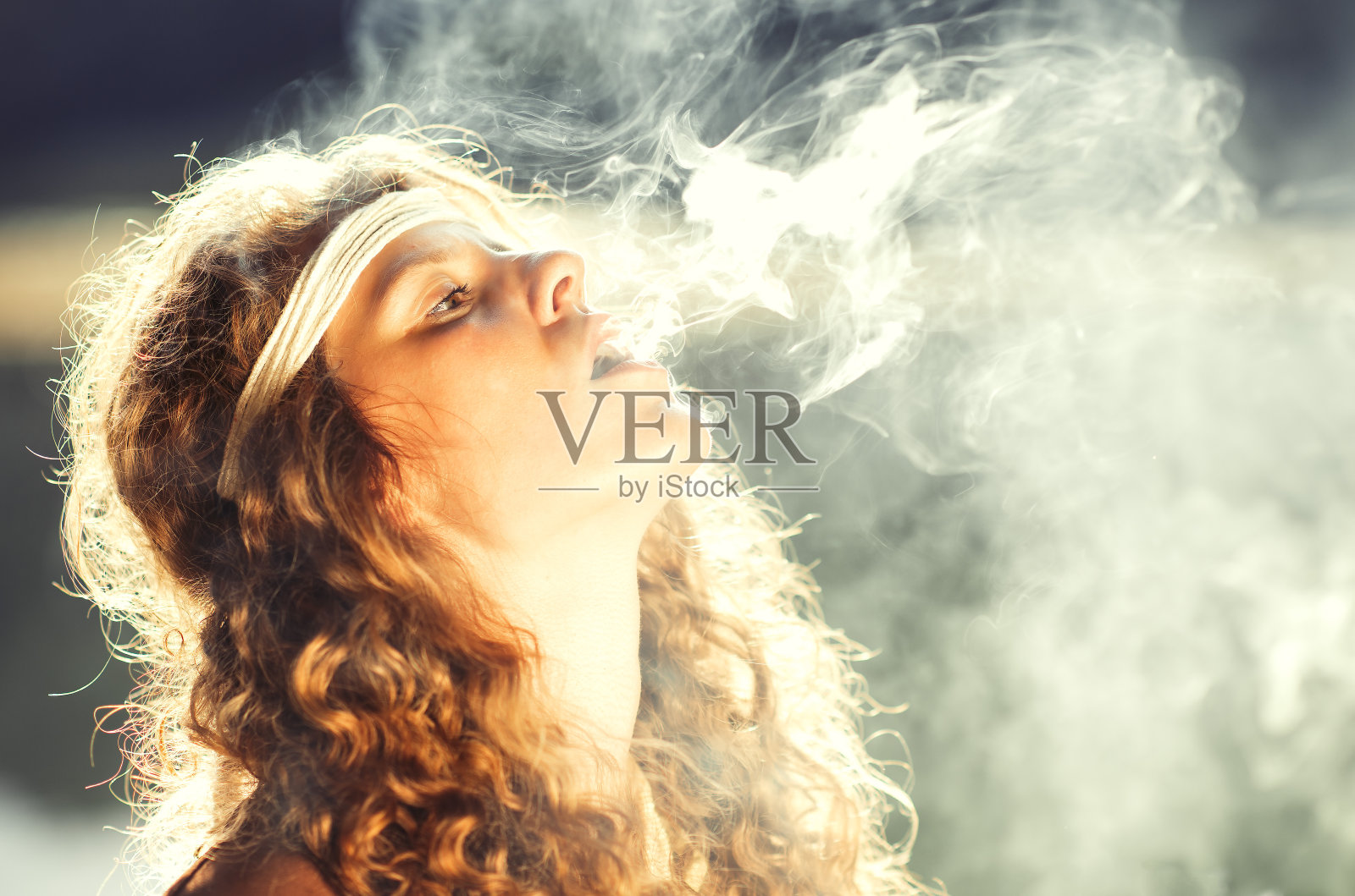 美丽自由的嬉皮女孩吹烟-复古效果照片照片摄影图片