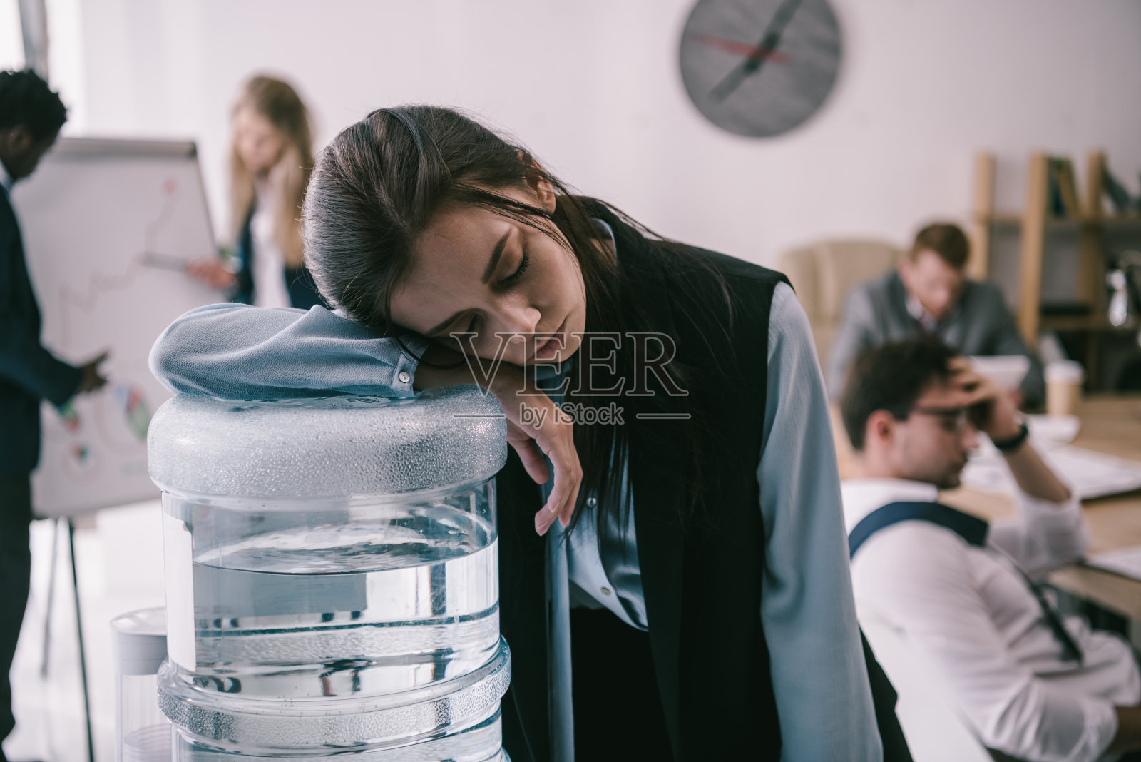 疲惫的僵尸经理靠在办公室的饮水机上照片摄影图片