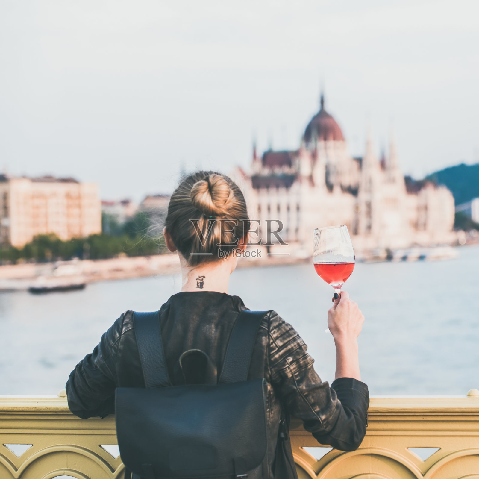 一个女人站在布达佩斯，手里拿着一杯葡萄酒照片摄影图片