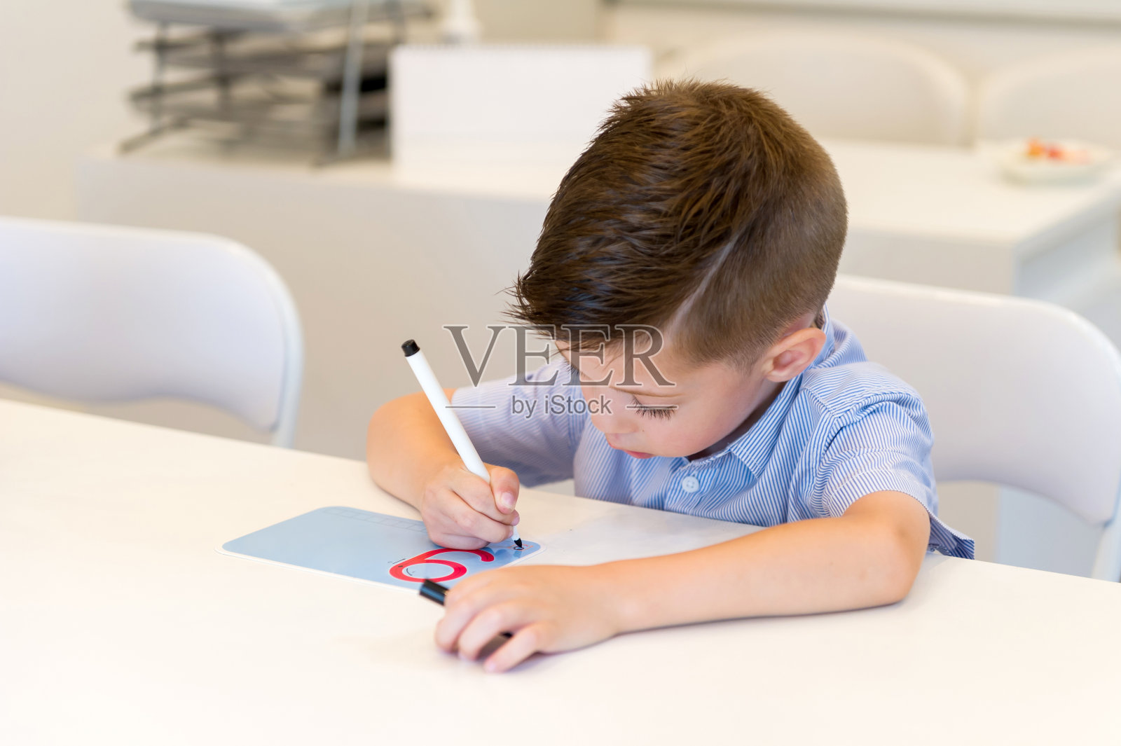 学龄前的小男孩在教室里学习写九号照片摄影图片