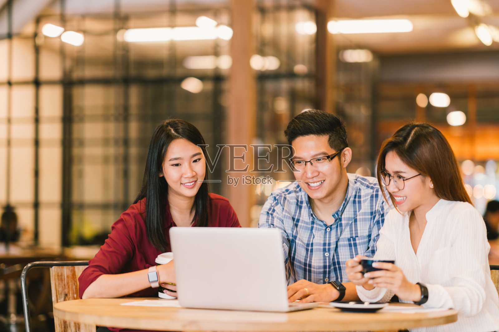 年轻的亚洲大学生群体或同事在咖啡馆或大学里一起使用笔记本电脑。休闲商务，自由职业，咖啡休息会议，电子学习或电子商务活动的概念照片摄影图片