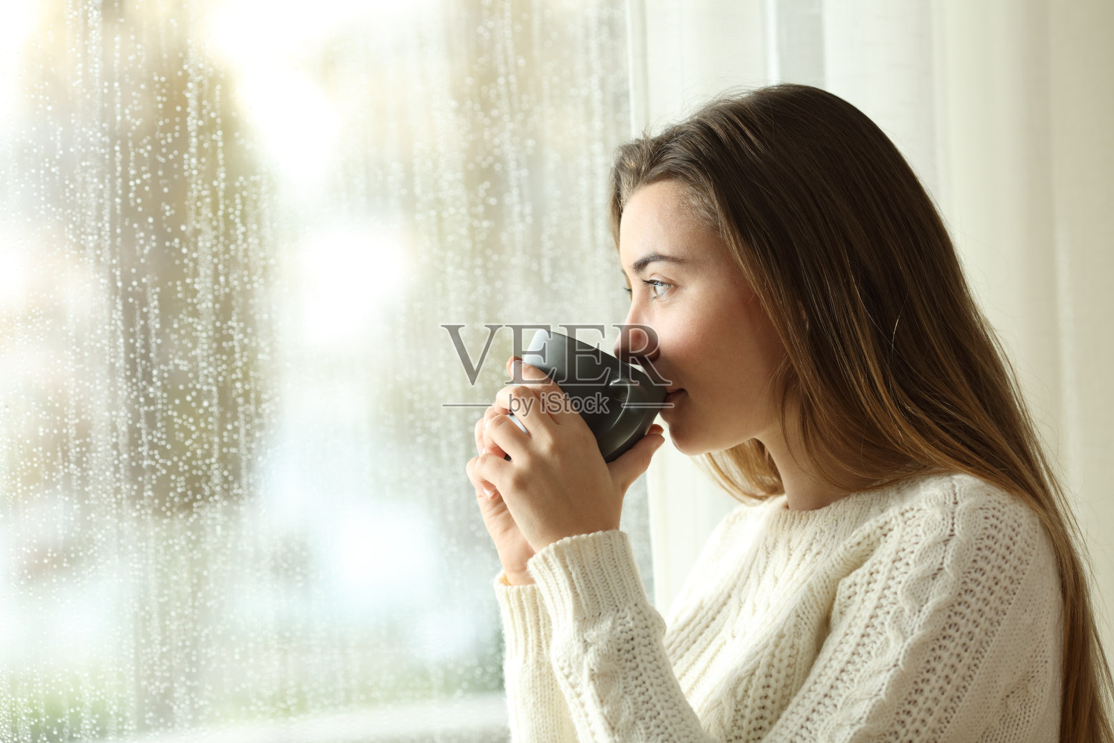 一个下雨天喝着咖啡望着窗外的青少年照片摄影图片