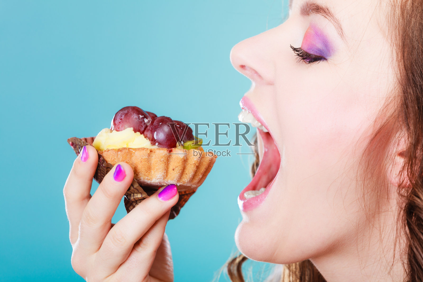 女人脸侧张着嘴吃蛋糕照片摄影图片