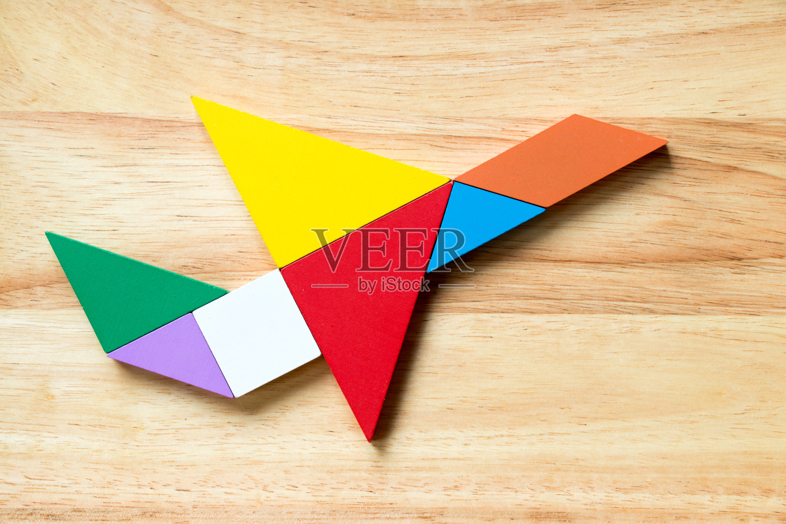 彩色七巧板拼图在飞行飞机形状的木材背景照片摄影图片