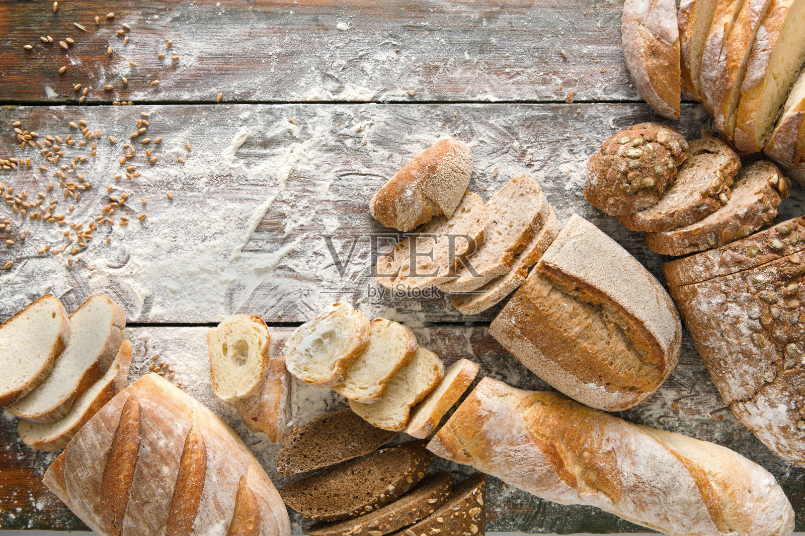 面包烘焙的背景。在乡村木材上的棕色和白色小麦谷物制成的面包照片摄影图片