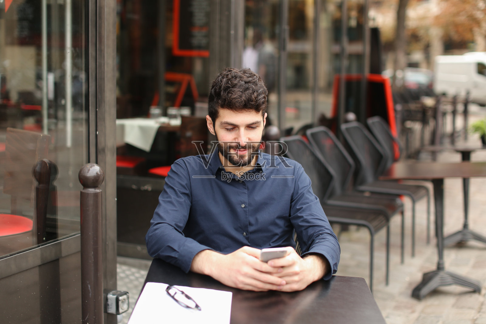 坐在咖啡桌旁用智能手机聊天的快乐男人照片摄影图片