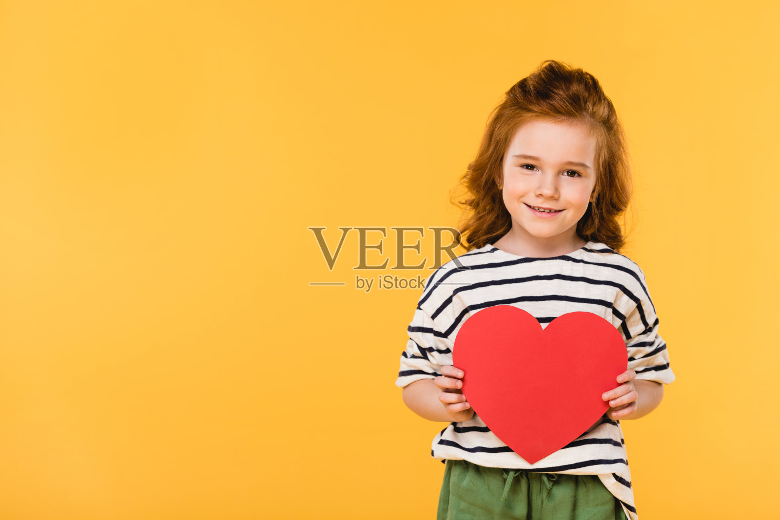孩子以红纸心隔黄，情人节概念照片摄影图片
