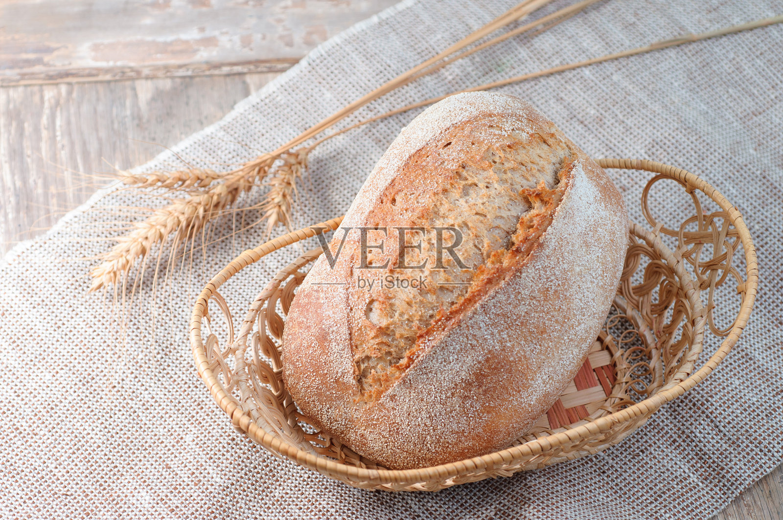 在旧的亚麻木制背景上放着刚烤好的面包。特写镜头食品摄影。照片摄影图片
