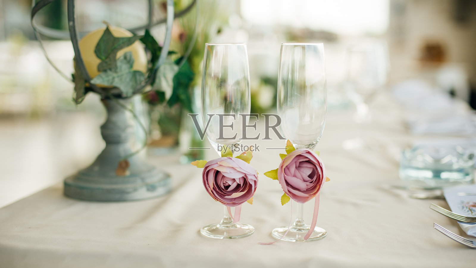 桌子上放着新婚夫妇用玫瑰装饰的玻璃杯照片摄影图片