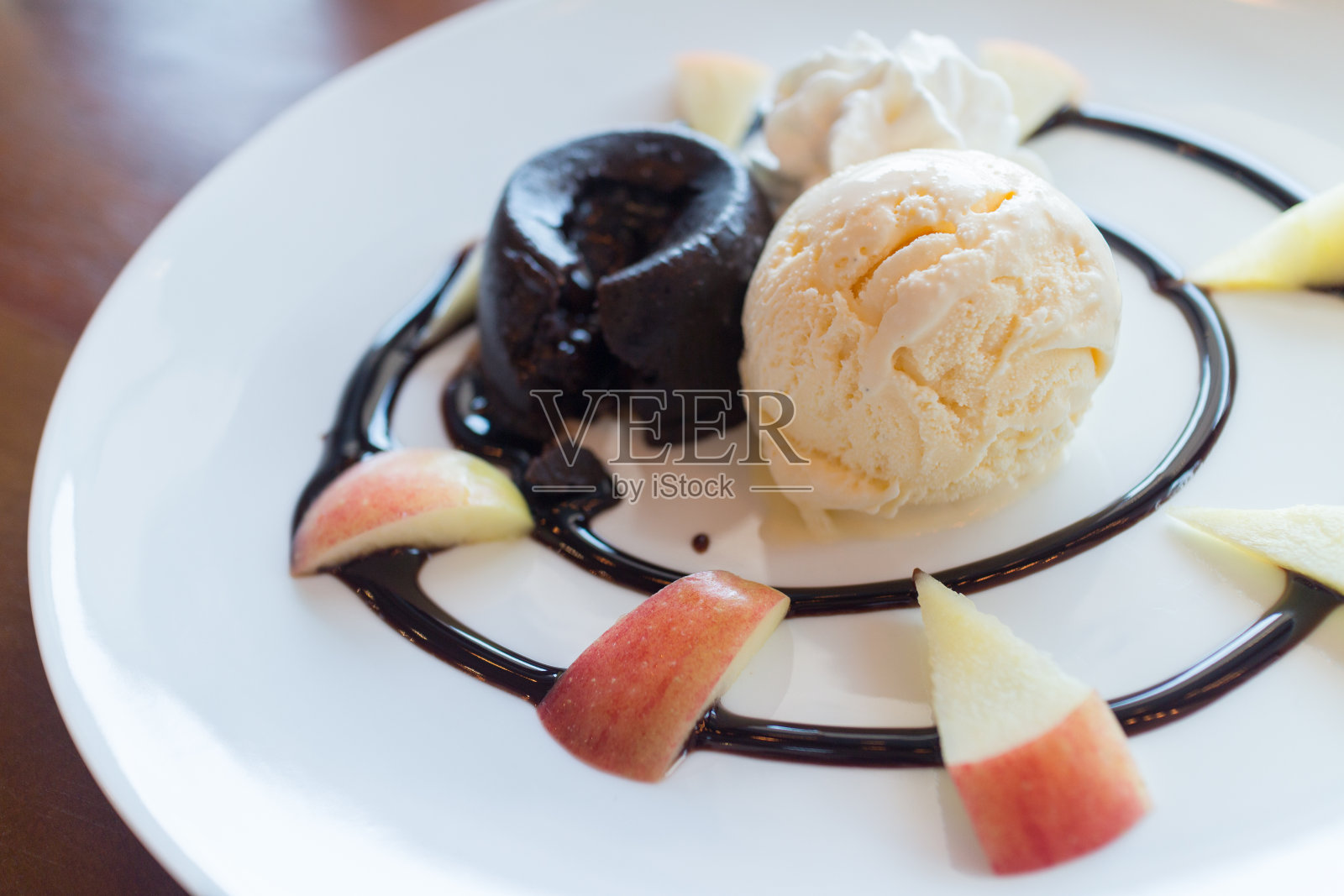 巧克力熔岩蛋糕，香草冰淇淋球，苹果和鲜奶油照片摄影图片