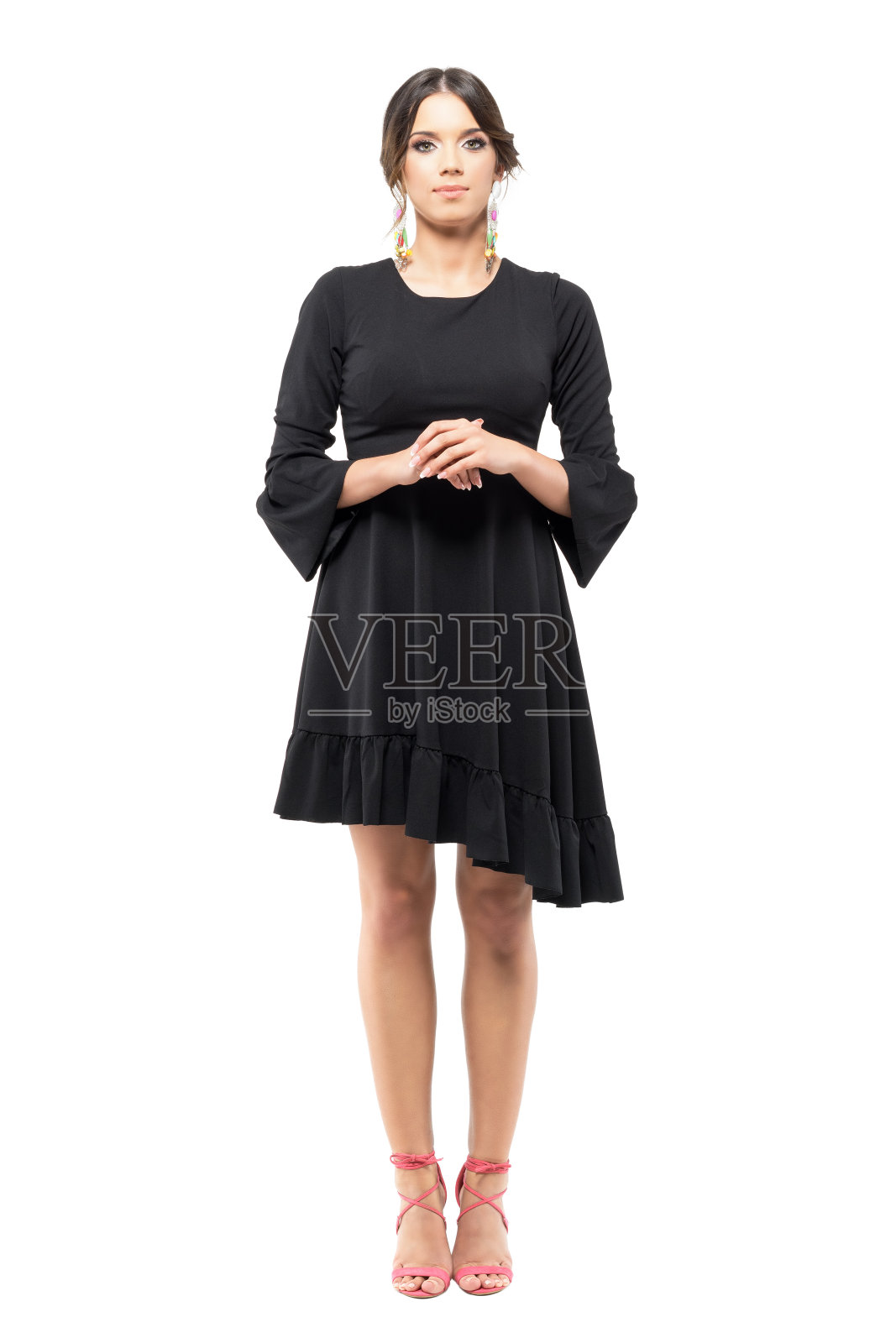 站着优雅的正式女人在黑色连衣裙与手紧握看着相机。照片摄影图片