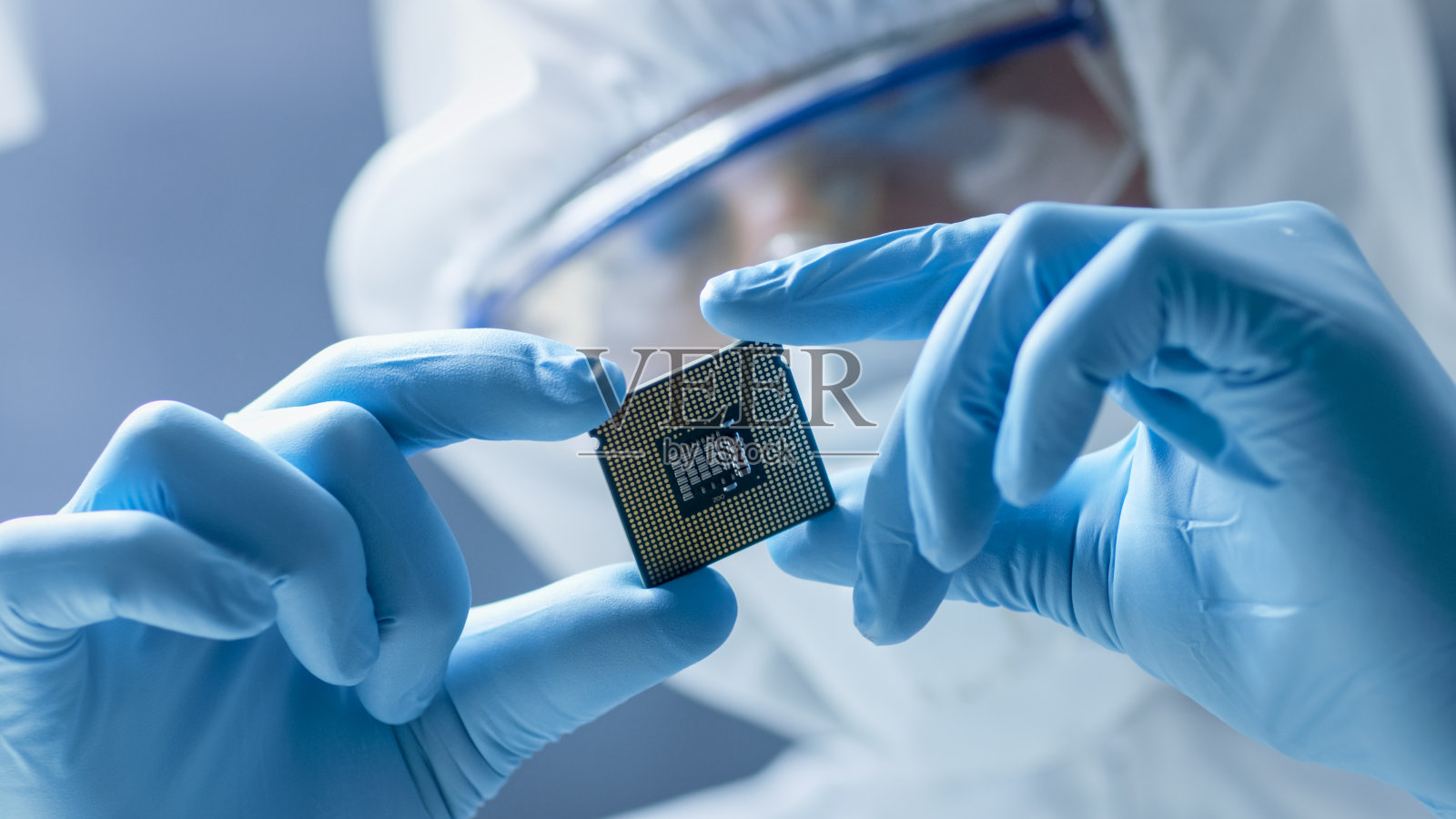 在超现代电子制造工厂，无菌工作服的设计工程师手持手套并检查微芯片。照片摄影图片