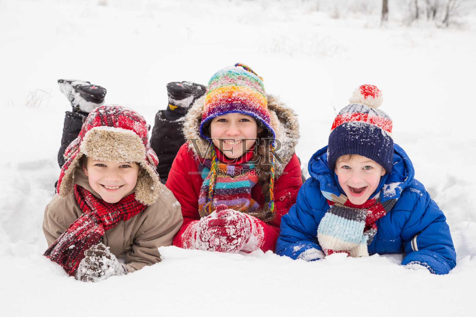 三个孩子一起躺在雪地上照片摄影图片